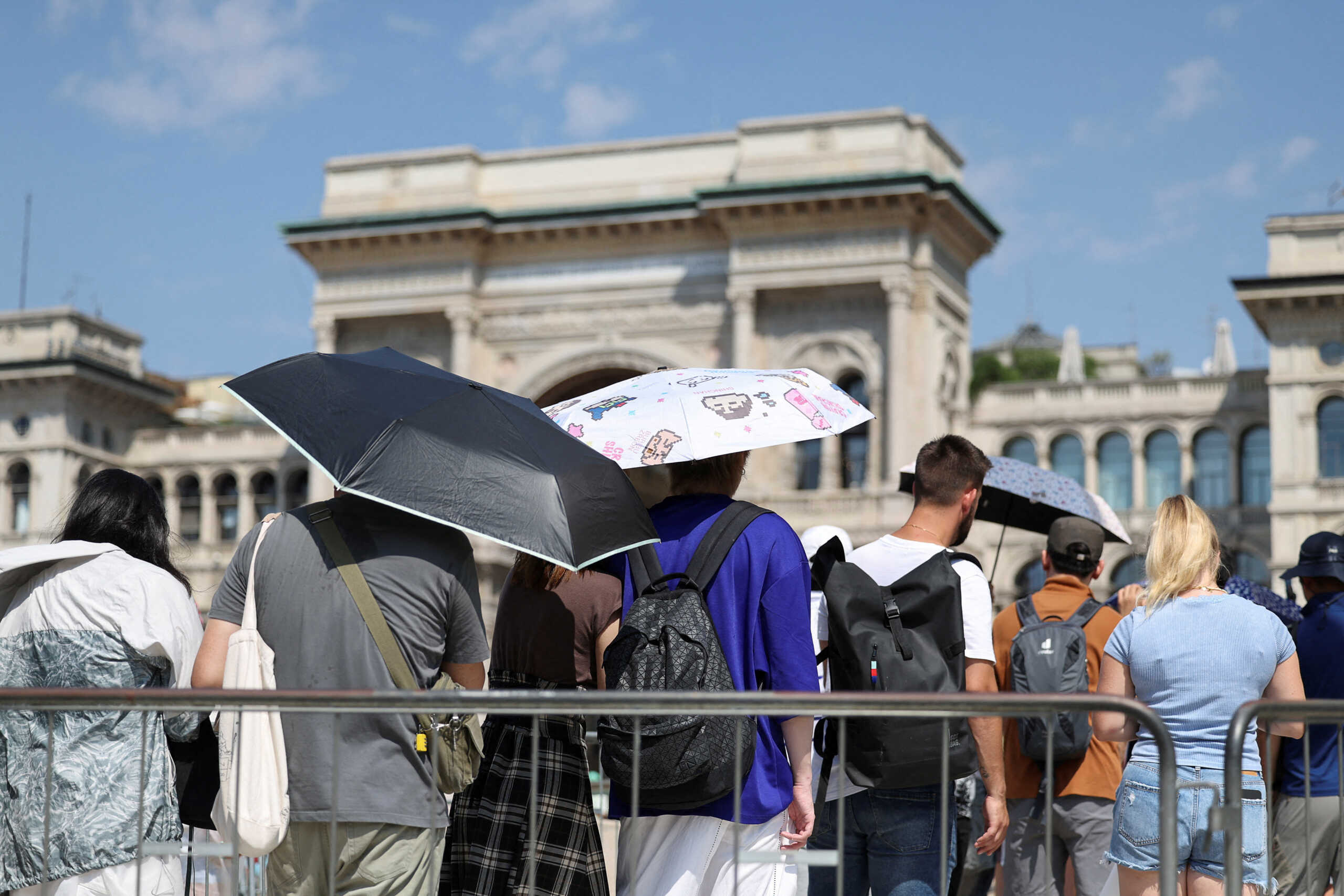 FILE PHOTO: People use umbrellas to hide from the sun, as they queue to enter the Milan's Duomo Cathedral, during a heatwave, in Milan, Italy, August 21, 2023. REUTERS