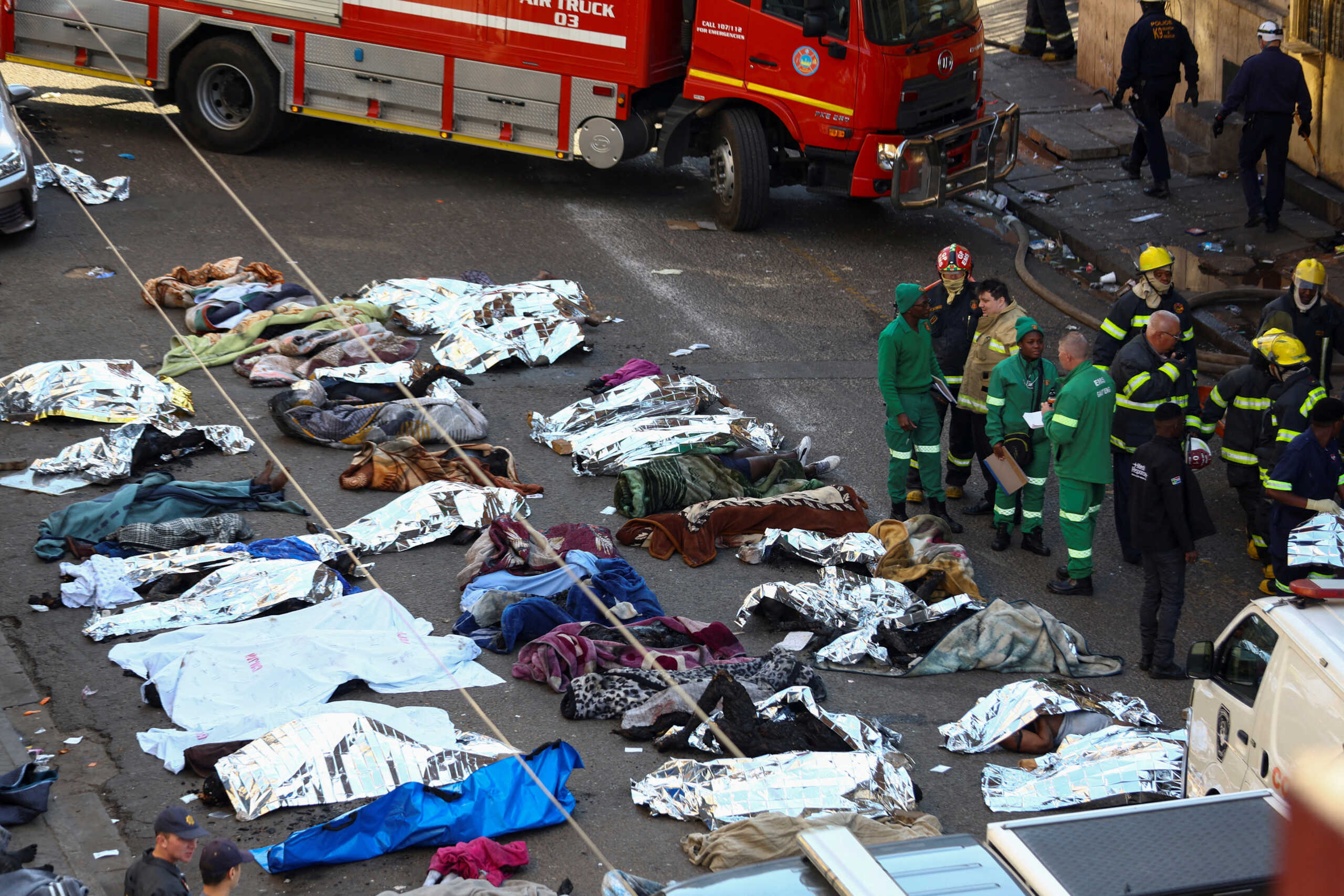 SENSITIVE MATERIAL. THIS IMAGE MAY OFFEND OR DISTURB  Rescuers and firefighters stand next to the bodies of victims at the scene of a deadly blaze, in Johannesburg, South Africa August 31, 2023. REUTERS