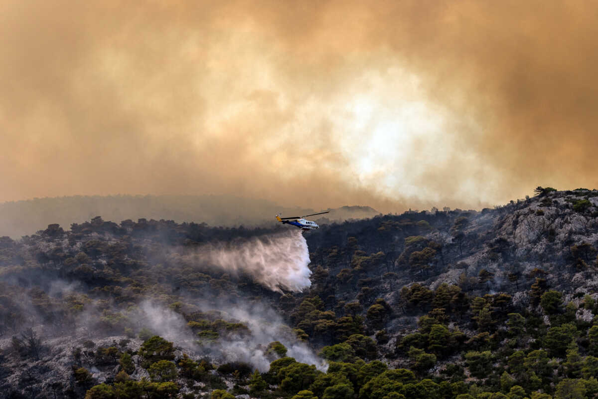A firefighting helicopter makes a water drop, as a wildfire burns in Menidi, near Athens, Greece, August 23, 2023. REUTERS