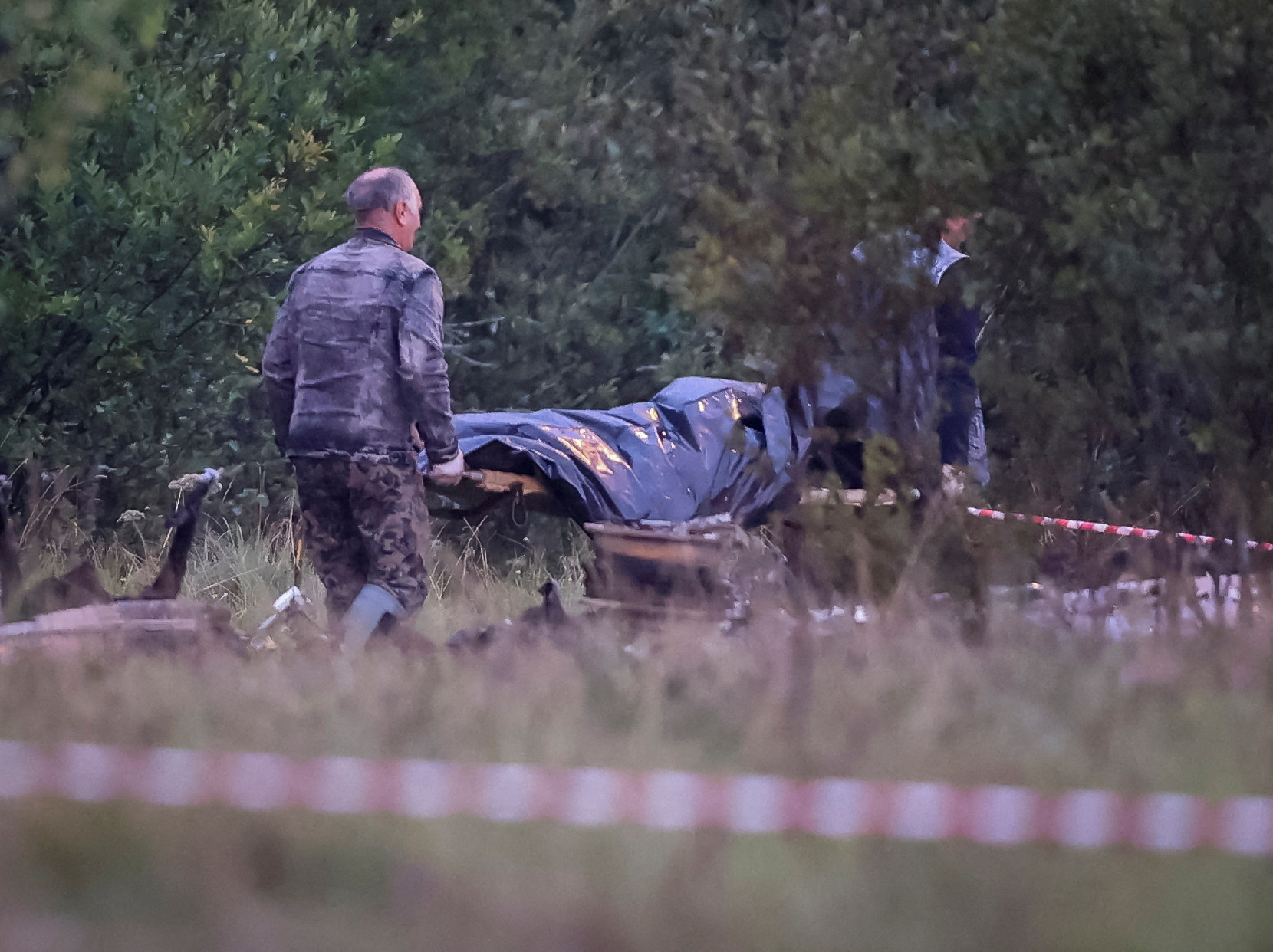 Emergency specialists carry a body bag near wreckages of the private jet linked to Wagner mercenary chief Yevgeny Prigozhin at the crash site in the Tver region, Russia, August 24, 2023. REUTERS