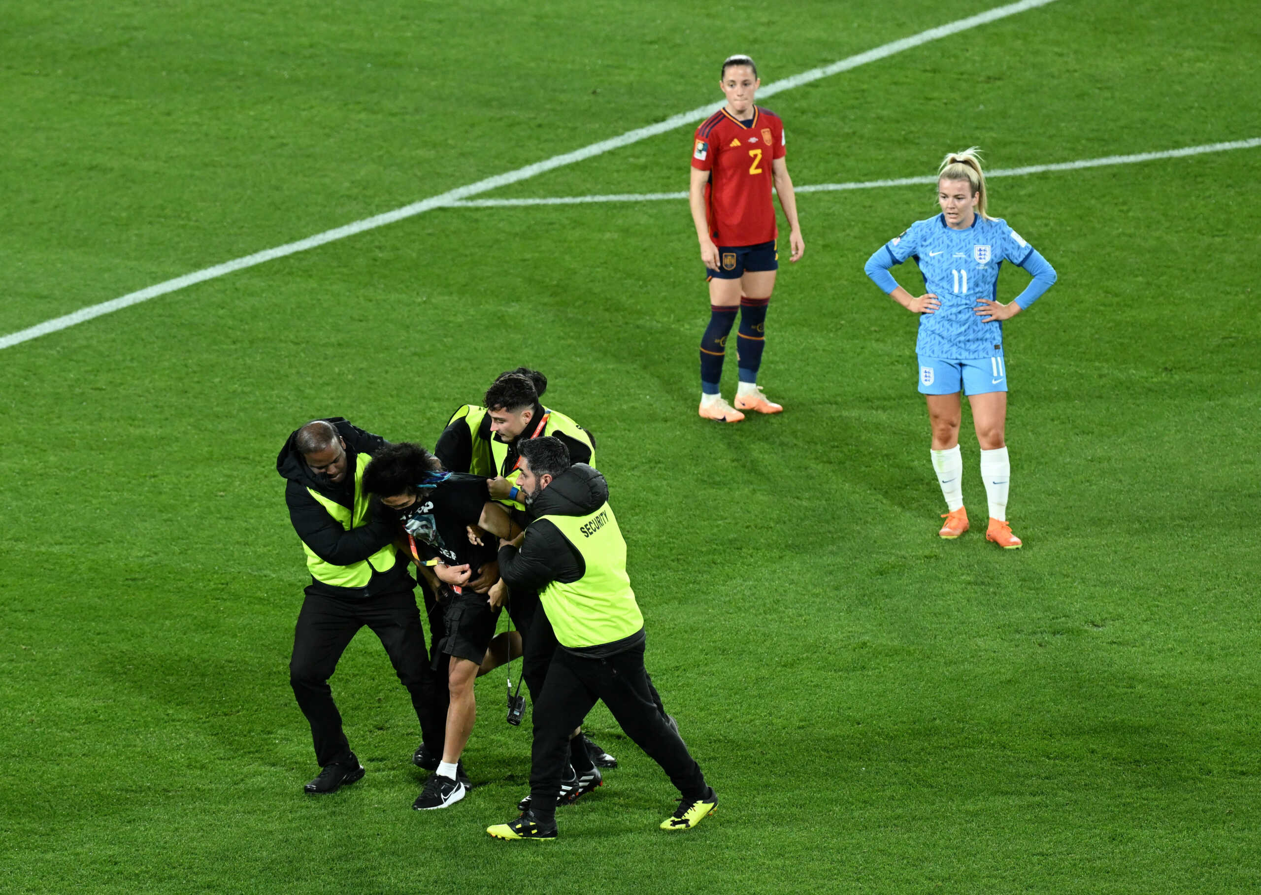 Soccer Football - FIFA Women's World Cup Australia and New Zealand 2023 - Final - Spain v England - Stadium Australia, Sydney, Australia - August 20, 2023 A pitch invader wearing a shirt in protest against Russia's president Vladimir Putin is detained by stewards REUTERS