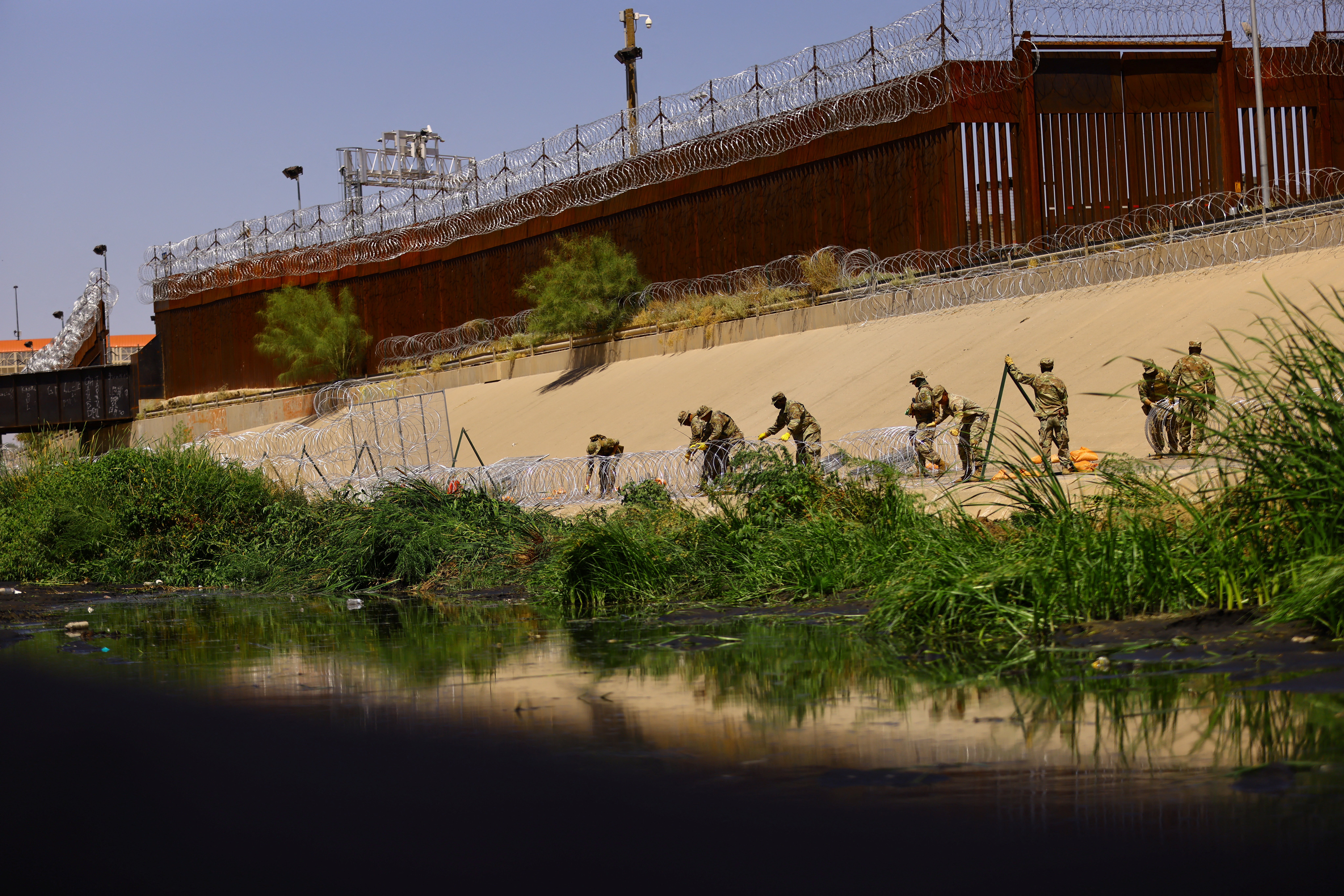 Members of the Texas National Guard place razor wire on the banks of the Rio Bravo River, the border between the United States and Mexico, with the purpose of reinforcing border security and inhibiting the crossing of migrants into the United States, as seen from Ciudad Juarez, Mexico, July 27, 2023. REUTERS