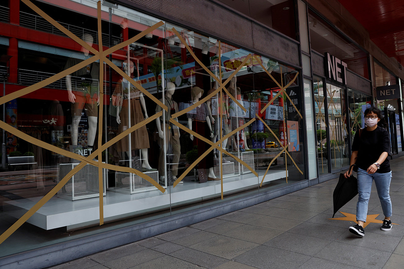 A woman walks past a closed store with taped windows amid warnings of floods and high winds in northern Taiwan due to Typhoon Khanun, in Taipei, Taiwan, August 3, 2023. REUTERS