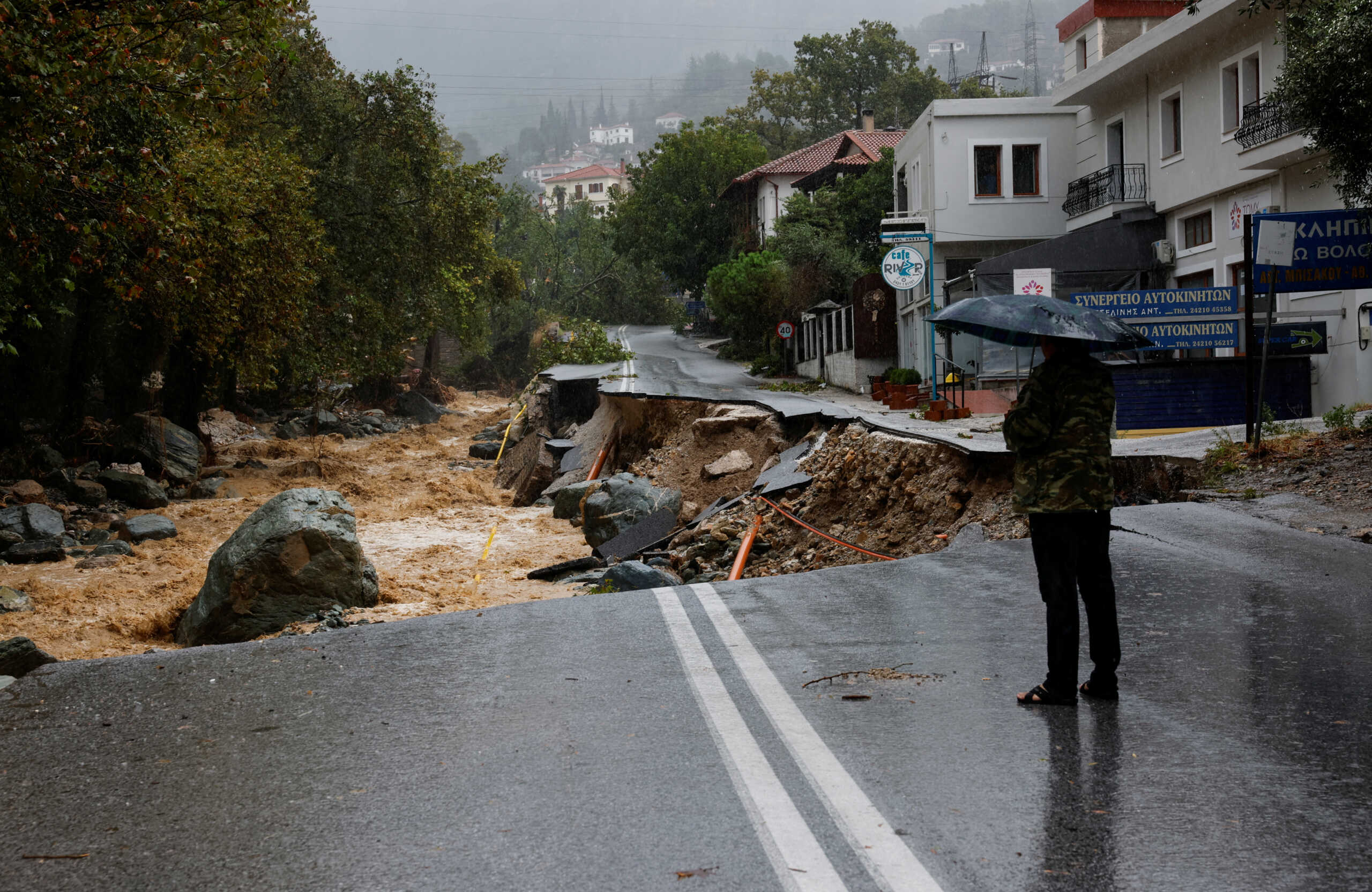 A person stands on a road which collapsed due to the impact of storm Daniel, near a nursing home in the city of Volos, Greece, September 6, 2023. REUTERS