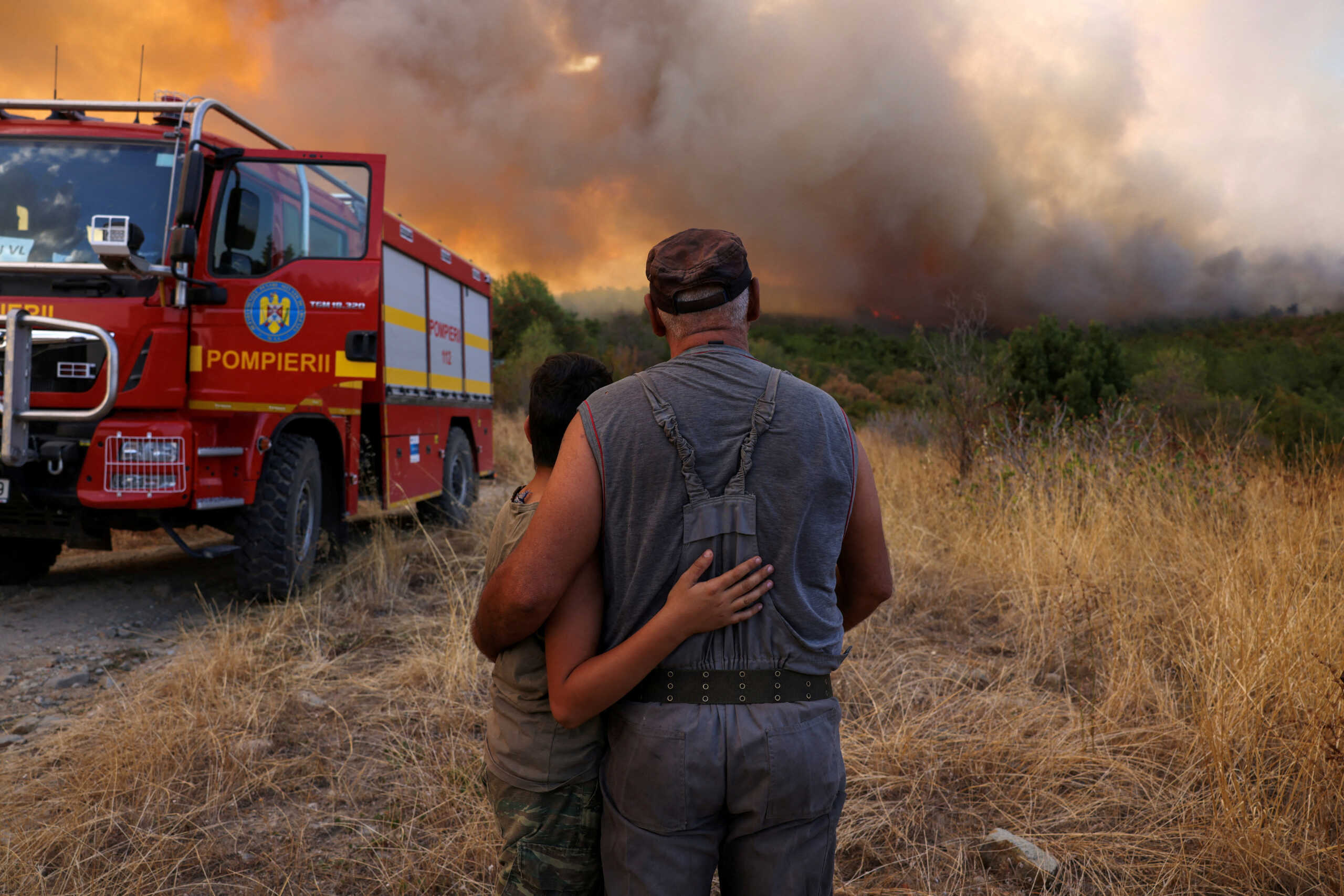 Panagiotis Arabatzis, 57, hugs his son Stamatis, 13, as they watch smoke rising from a wildfire burning near the village of Lefkimi in the region of Evros, Greece, September 2, 2023. REUTERS