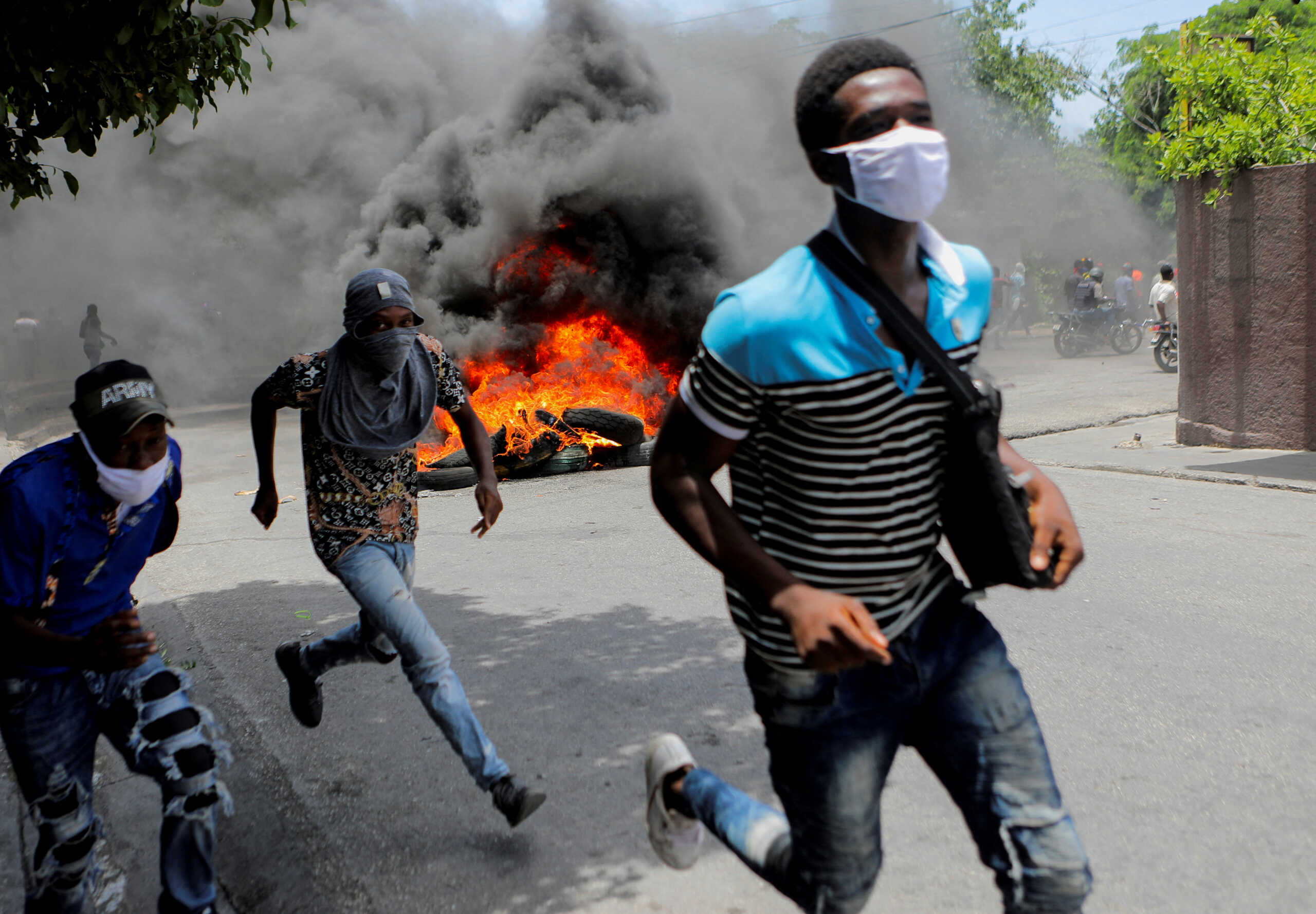 Men run next to burning tires during a protest demanding an end to gang violence, in Port-au-Prince, Haiti, August 14, 2023. REUTERS