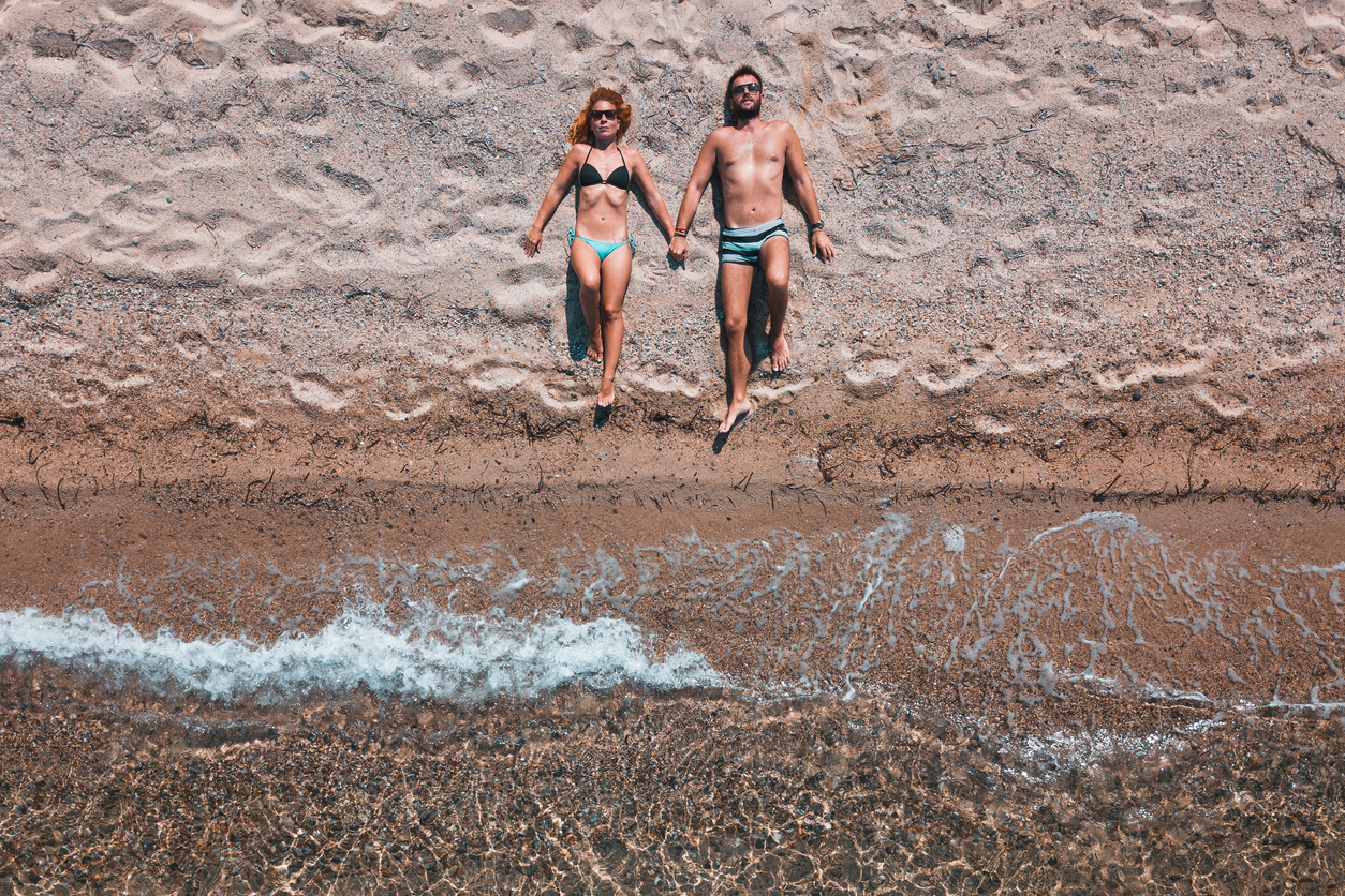 Aerial view on a young couple lying on the beach