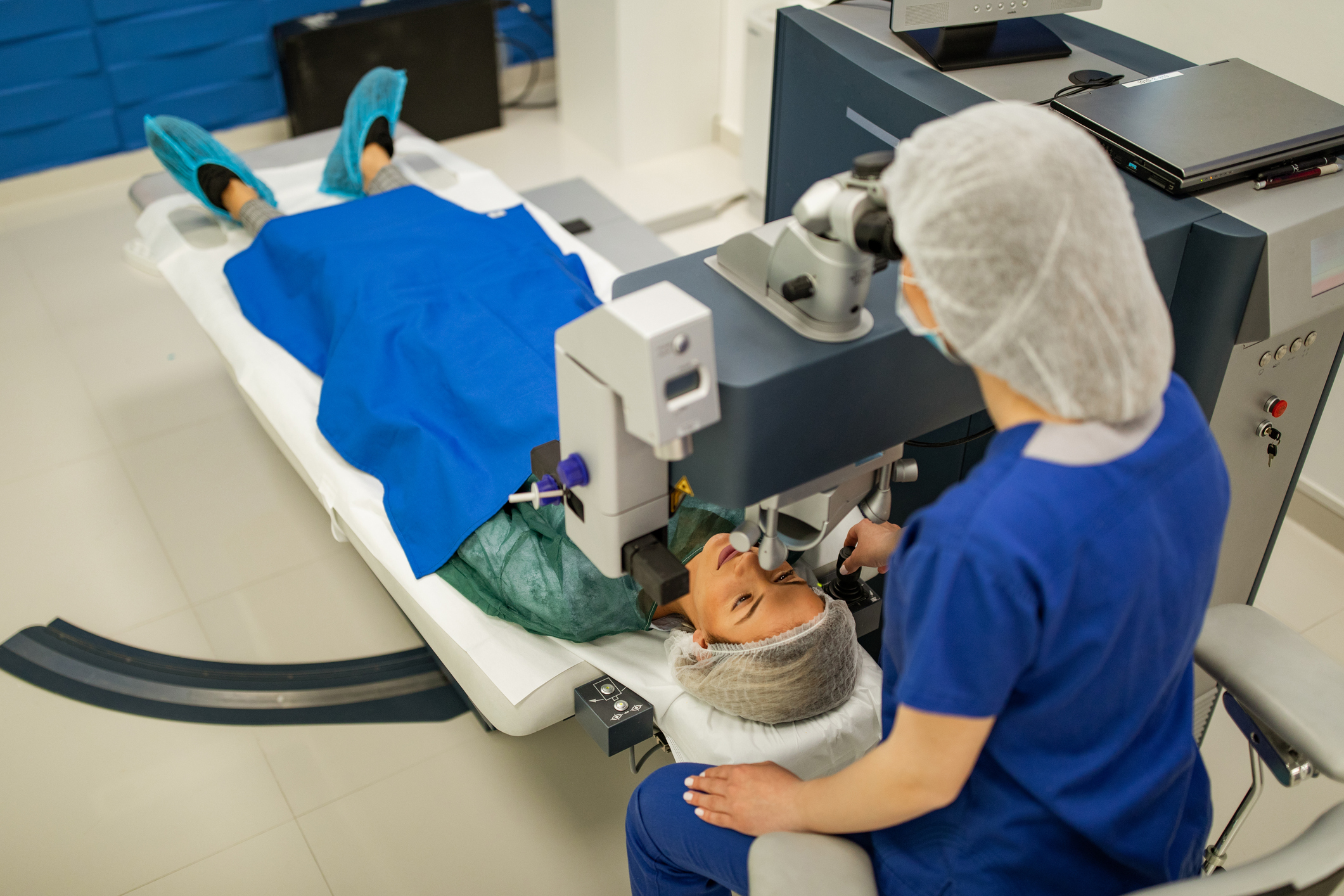 Young female surgeon performing laser eye surgery on a young female patient in modern clinic