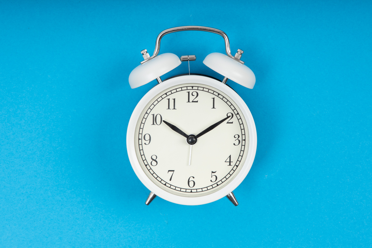 Retro alarm clock on blue background. Old fashioned alarm clock