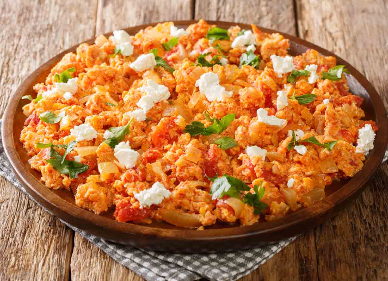 Greek Fresh Tomato and Feta Egg Scramble Kagiana or Strapatsada closeup in the plate on the table. horizontal