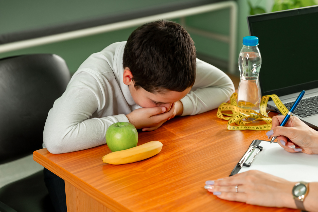 Prescribing diet for overweight fat patient. Doctor warning of consequences. Doctor advising a fat boy to eat healthy. Child eating stealthily high calorie foods. Obesity, health problem, weight loss.