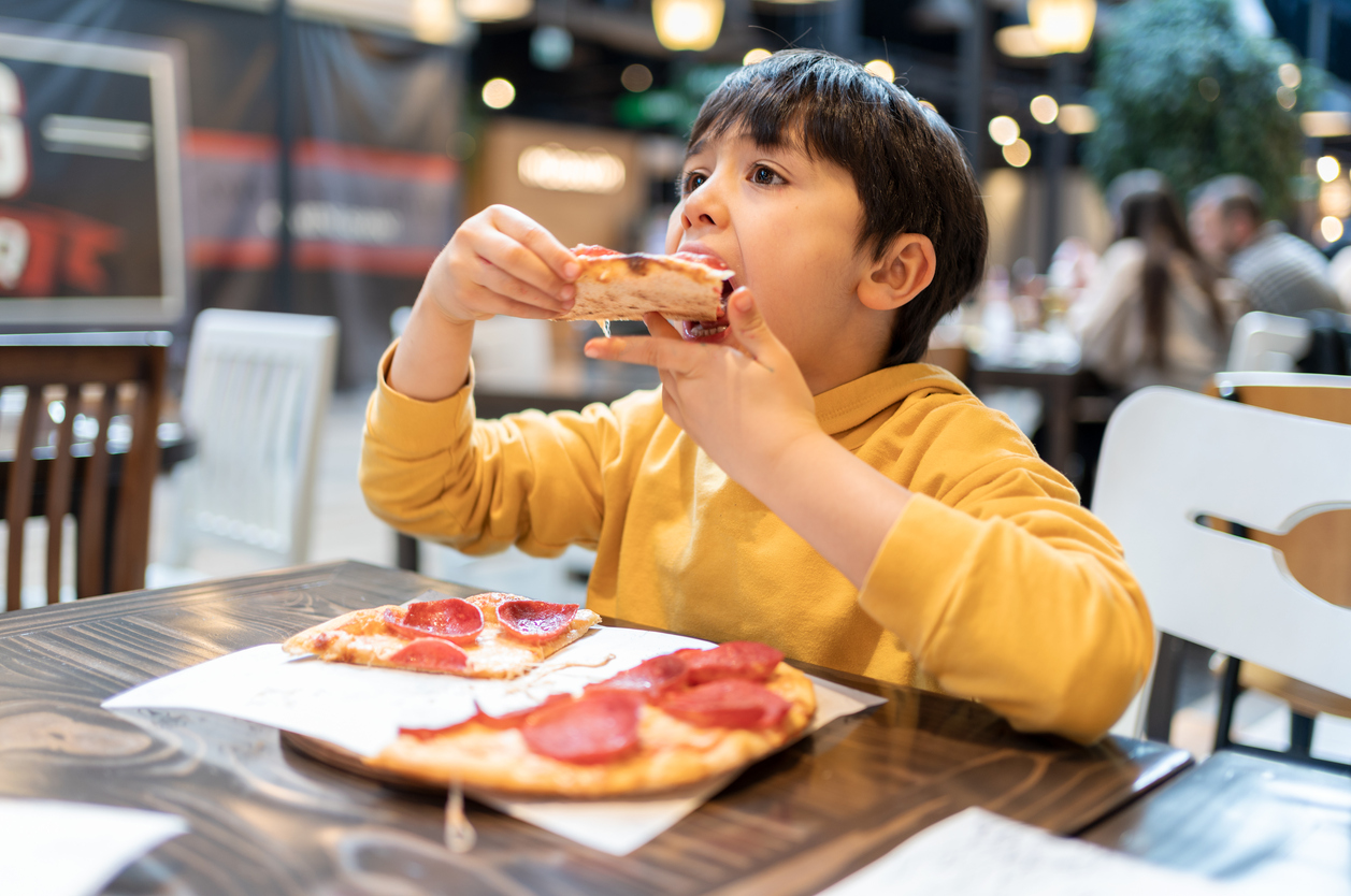 Little Child Eating Pizza At Restaurant