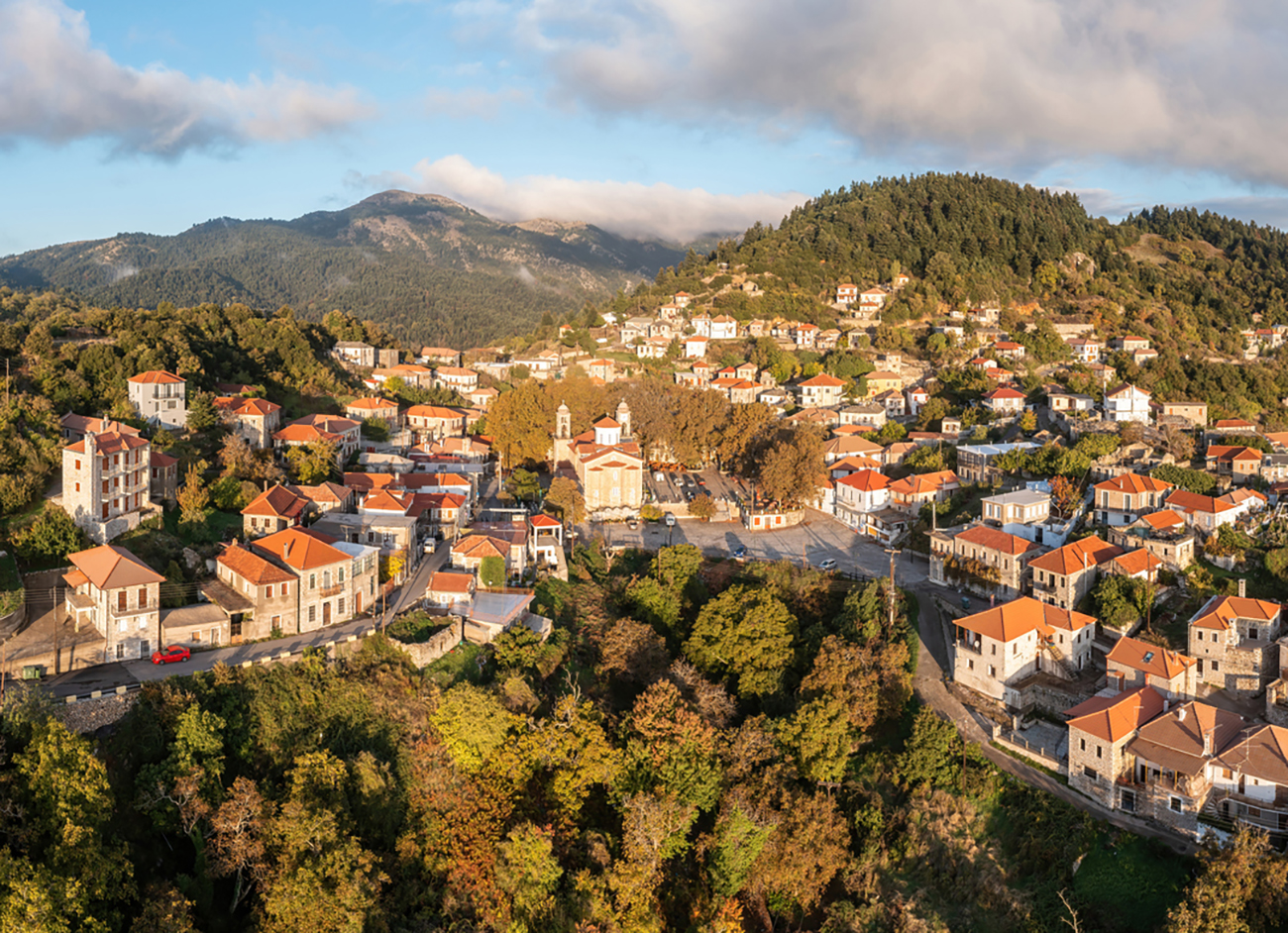 Greece village Kosmas on mountain Parnonas aerial drone view, Peloponnese. Traditional tile roof and stone wall buildings, cloudy blue sky, Autumn