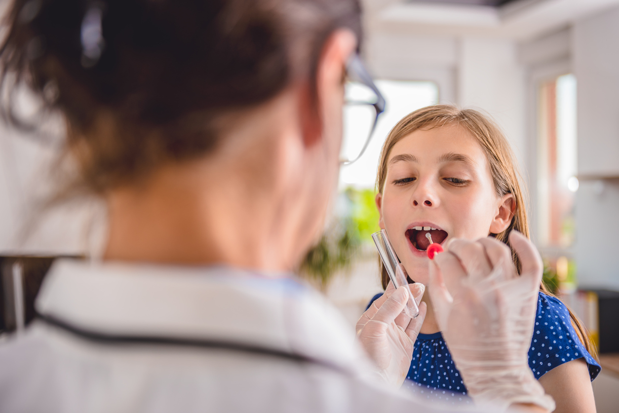 Female pediatrician using a swab to take a sample from a patient's throat