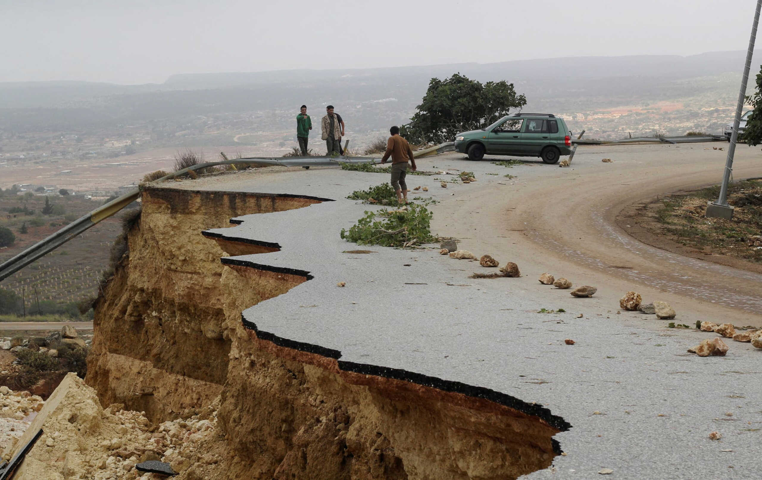 People stand in a damaged road as a powerful storm and heavy rainfall flooded hit Shahhat city, Libya, September 11, 2023. REUTERS