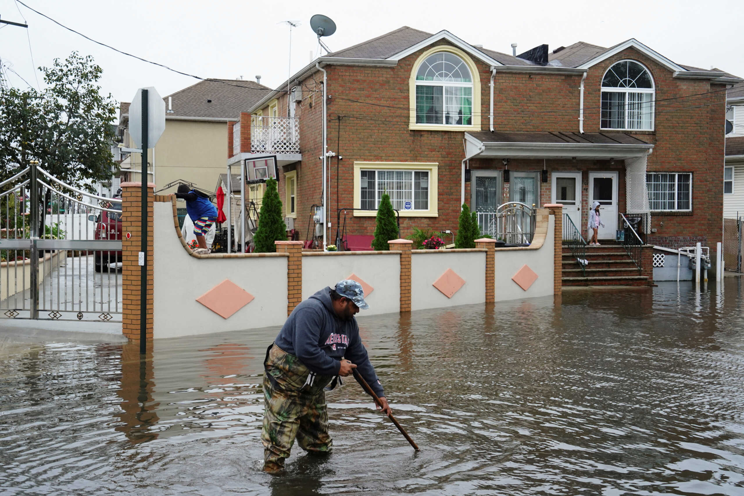 A resident surnamed Mahamad, a driving instructor and bus driver, attempts to unclog leaves and other debris from drainage holes in the flooded street of Rau Court, as the remnants of Tropical Storm Ophelia bring flooding across the mid-Atlantic and Northeast, in the Hamilton Beach neighborhood in the Queens borough of New York City, U.S., September 29, 2023.  REUTERS