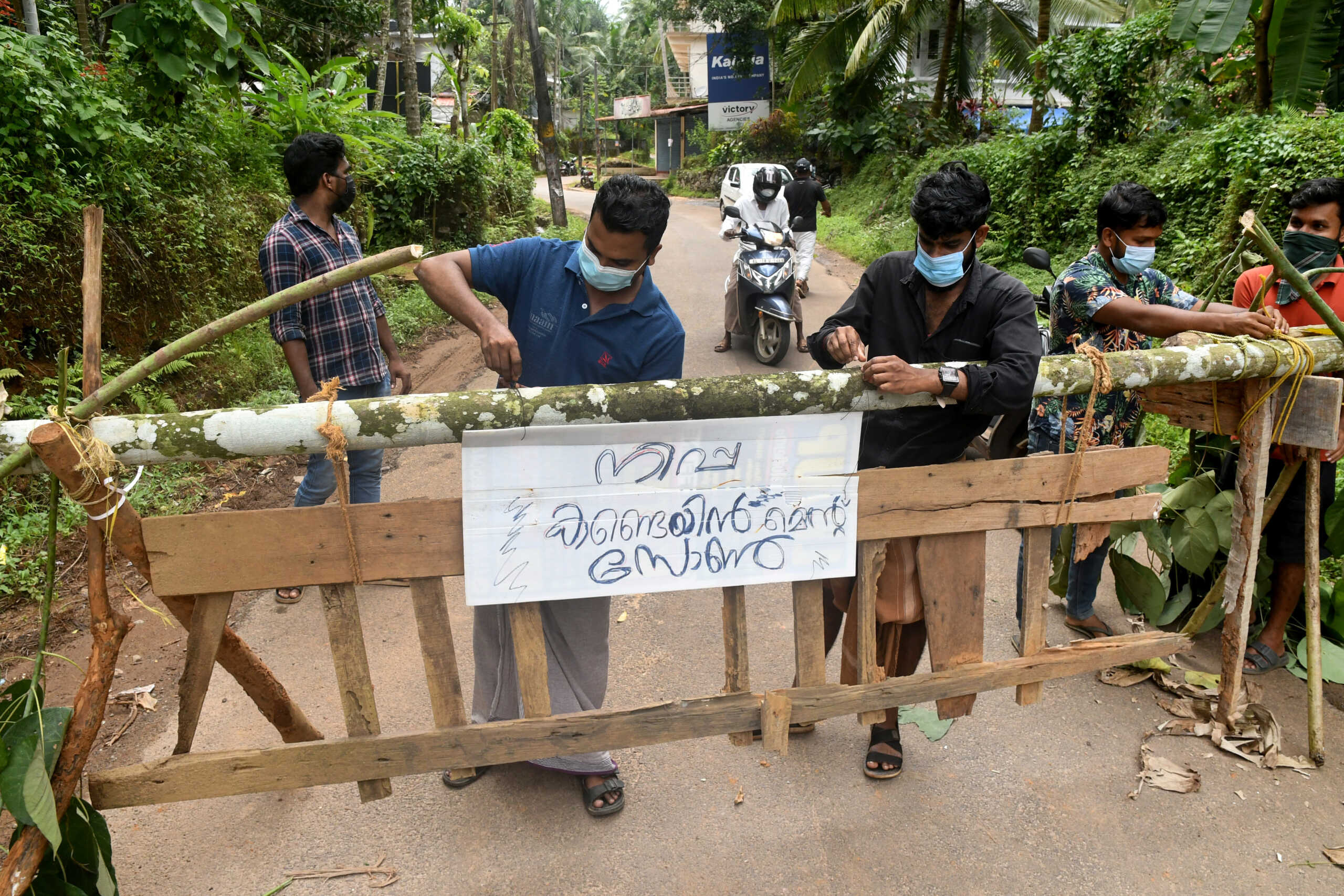 Residents fix a sign reading "Nipah containment zone" on a barricade, put up to block a road after the authorities declared the area a containment zone, to prevent the spread of Nipah virus in Ayanchery village in Kozhikode district, Kerala, India, September 13, 2023. REUTERS