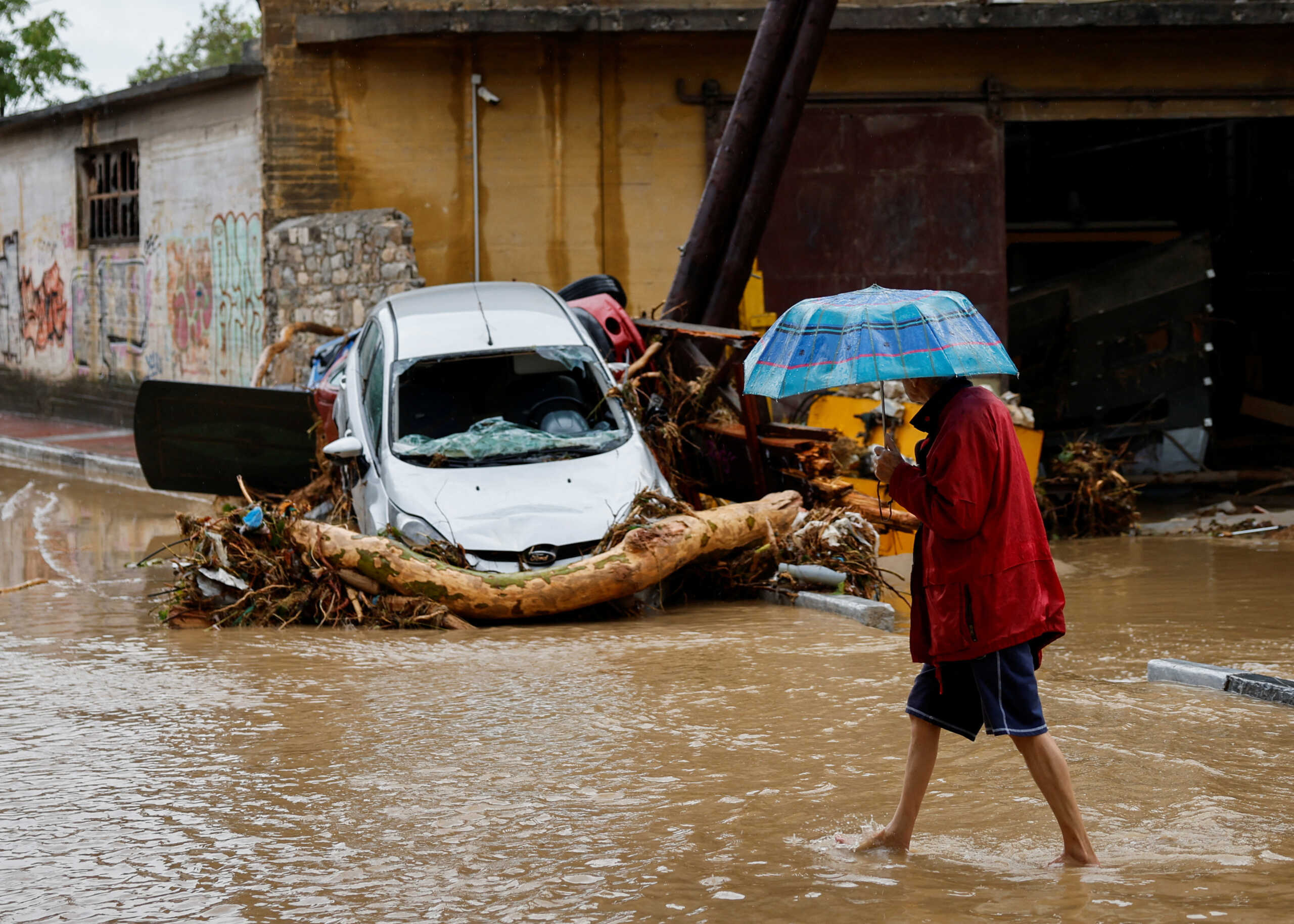 A man holding an umbrella walks on a road flooded due to the impact of storm Daniel, in the city of Volos, Greece, September 6, 2023. REUTERS