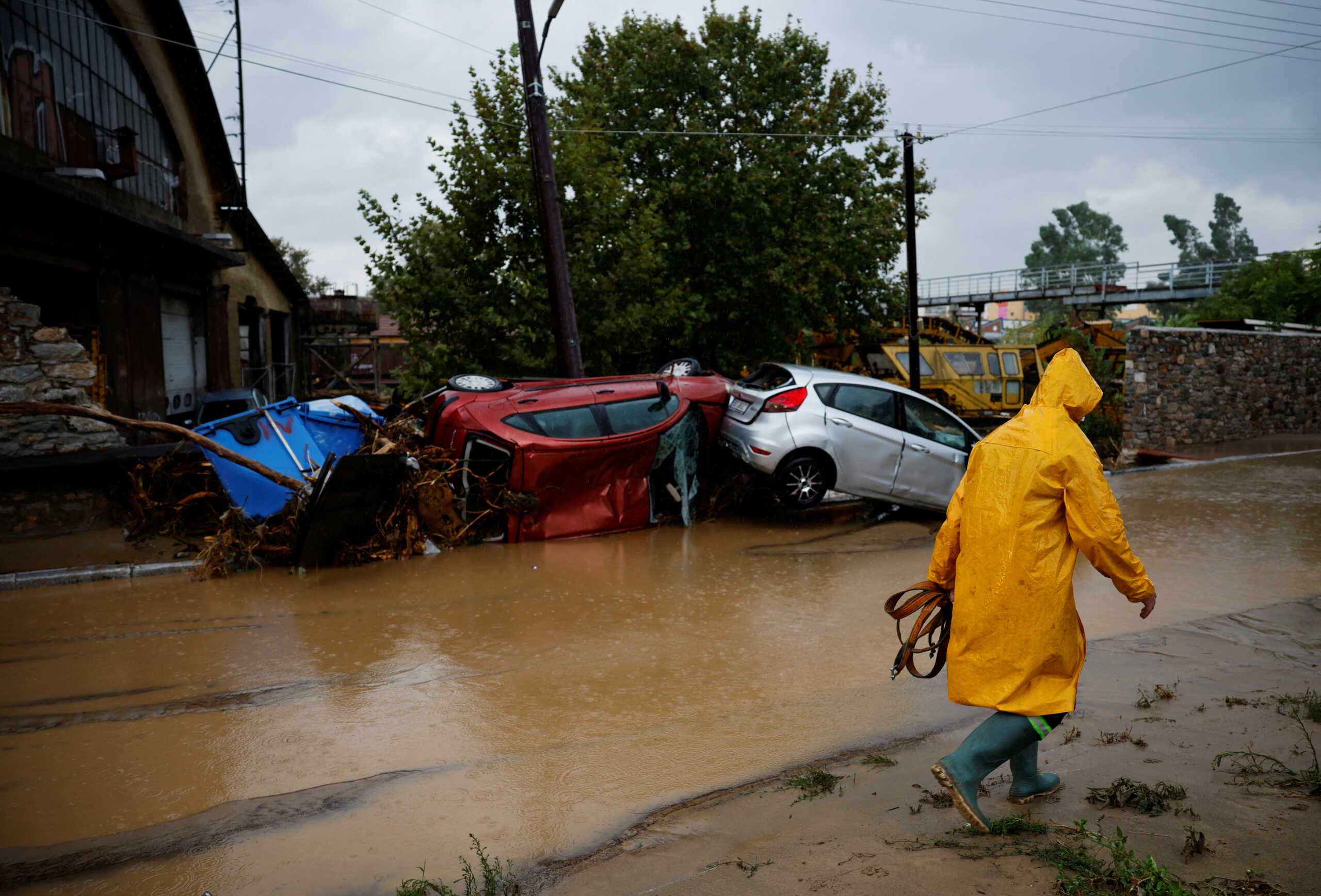 A fireman walks near damaged cars on a road flooded due to the impact of storm Daniel in the city of Volos, Greece, September 6, 2023. REUTERS