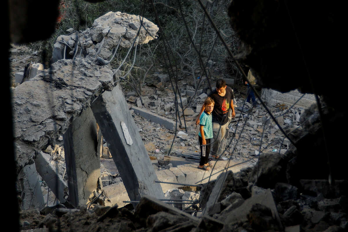 Palestinians stand on the rubble near a damaged house, following Israeli strikes, in Khan Younis in the southern Gaza Strip October 11, 2023. REUTERS
