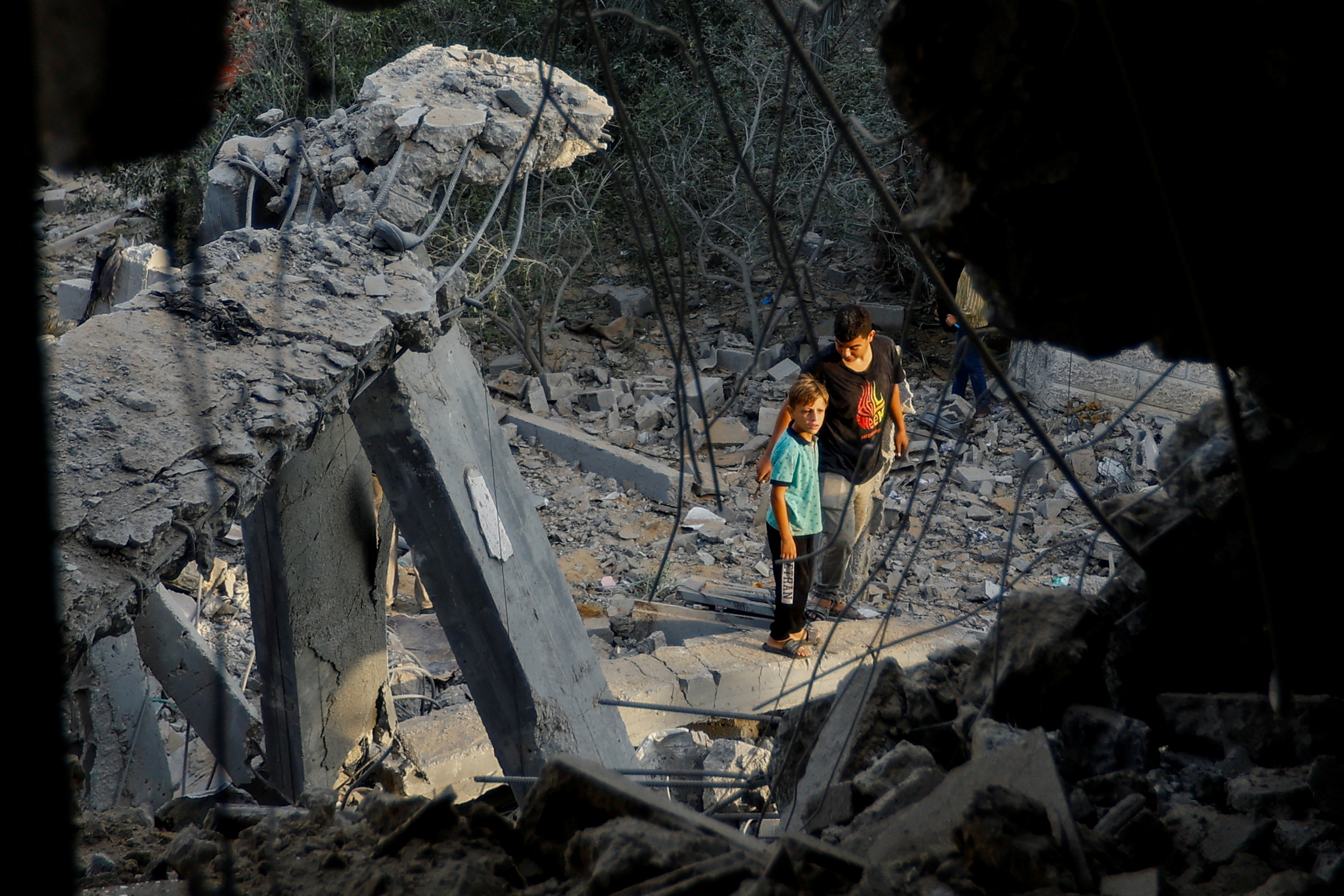 Palestinians stand on the rubble near a damaged house, following Israeli strikes, in Khan Younis in the southern Gaza Strip October 11, 2023. REUTERS