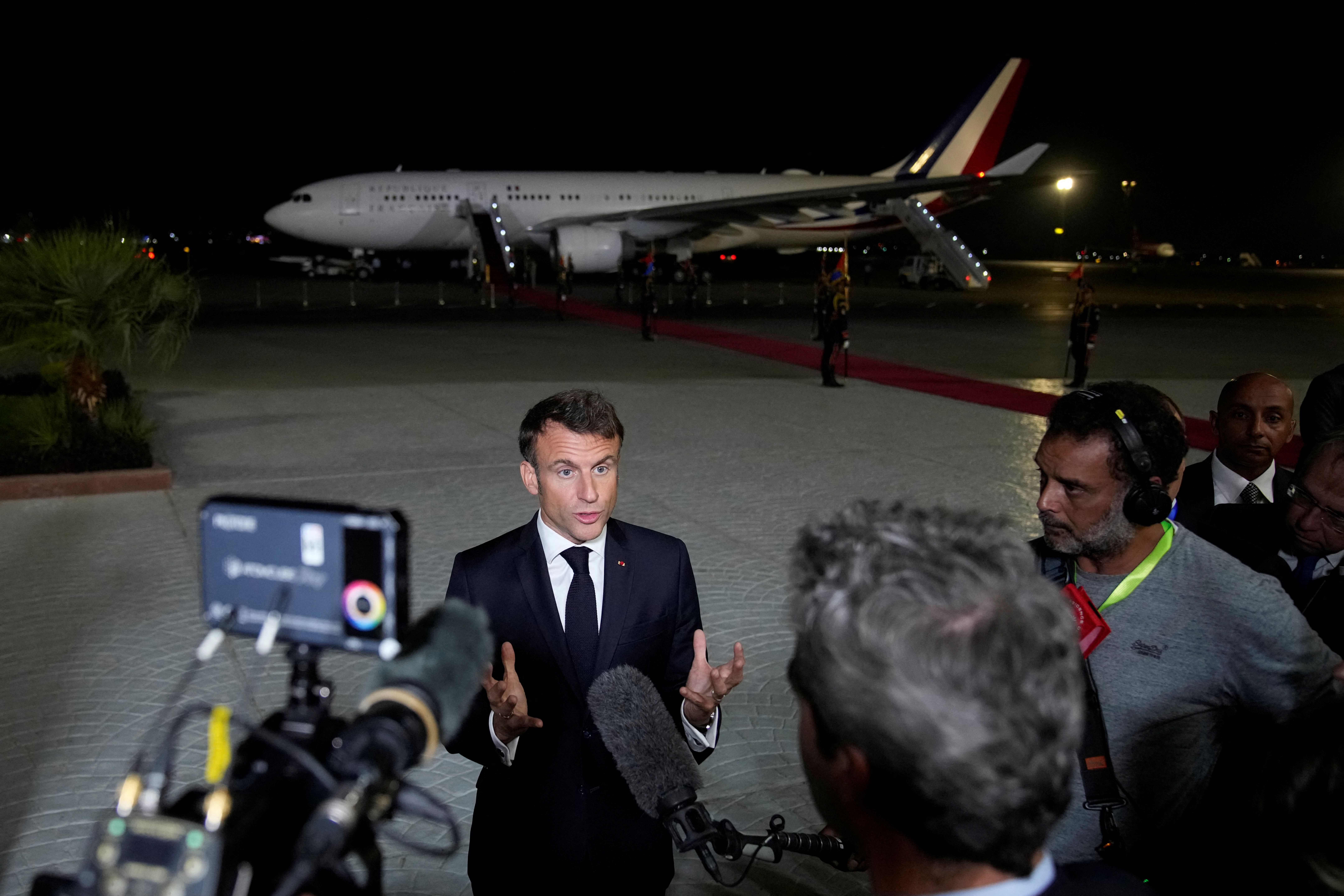French President Emmanuel Macron talks to journalists on the tarmac of Cairo airport, Egypt, as he departs Wednesday, Oct. 25, 2023. Christophe Ena