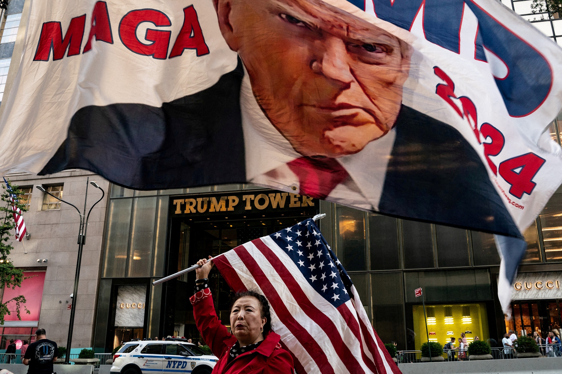 A supporter of former U.S. President Donald Trump holds up a U.S. national flag at Trump Tower in New York City, U.S., October 1, 2023. REUTERS