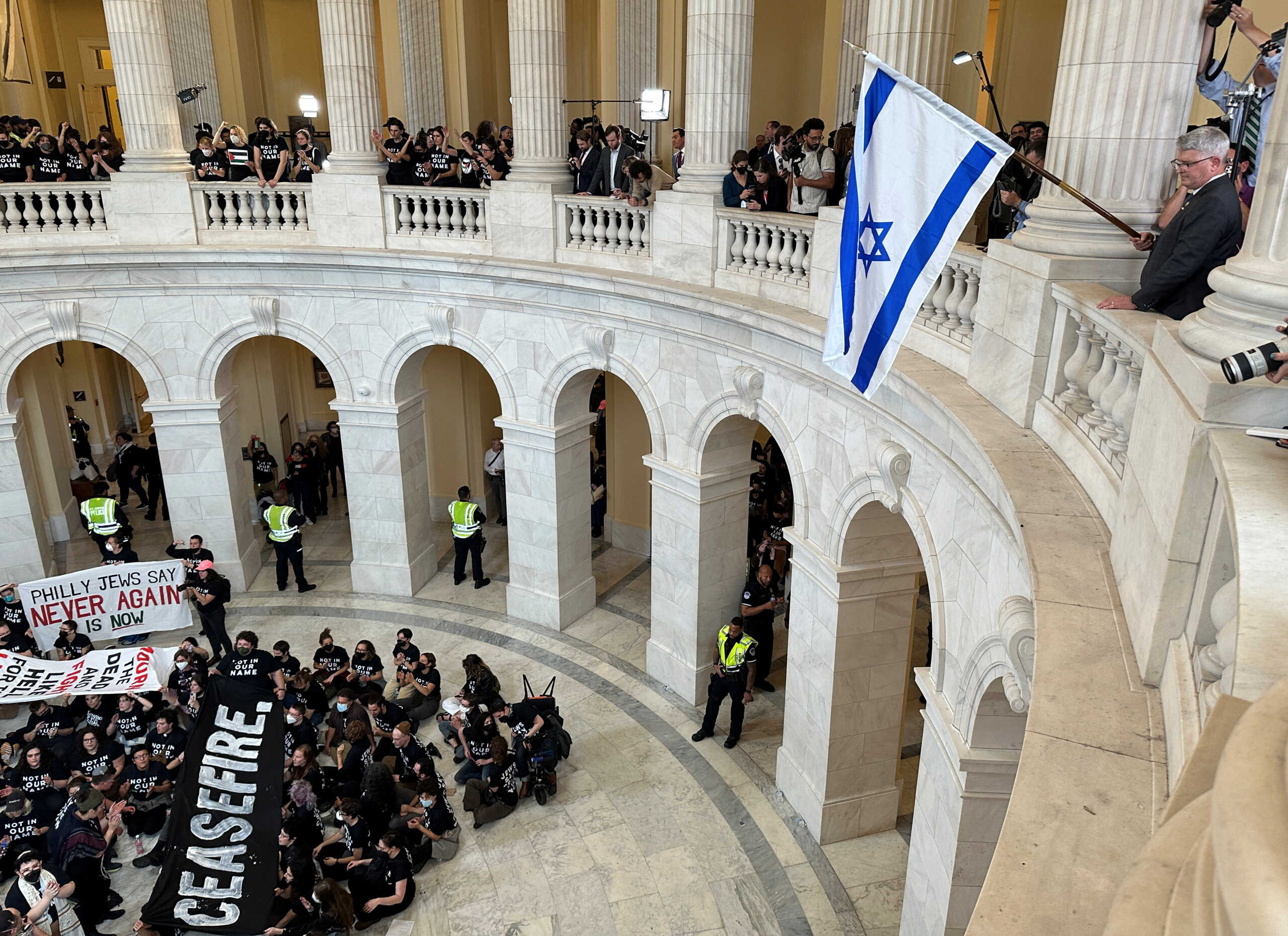 Rep. Brandon Williams (R-NY) dangles an Israeli flag over protesters, many of whom said they are Jewish, as they hold a civil disobedience action calling for a cease fire in Gaza and an end to the Israel-Hamas conflict while occupying the rotunda of the Cannon House office building on Capitol Hill in Washington, U.S., October 18, 2023. REUTERS