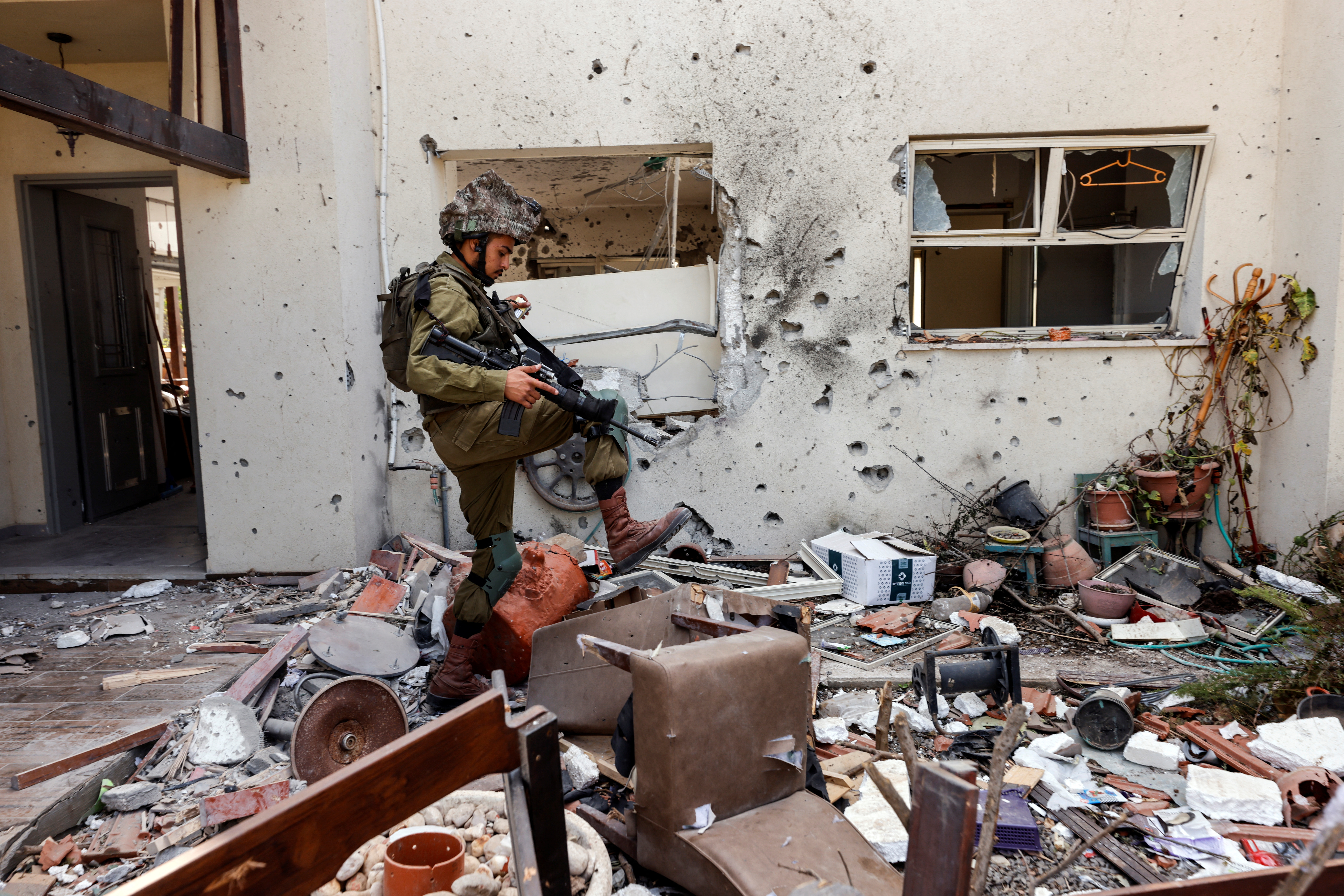 An Israeli soldier steps over personal belongings near a home, following a mass infiltration by Hamas gunmen from the Gaza Strip, in Kibbutz Beeri in southern Israel, October 13, 2023. REUTERS