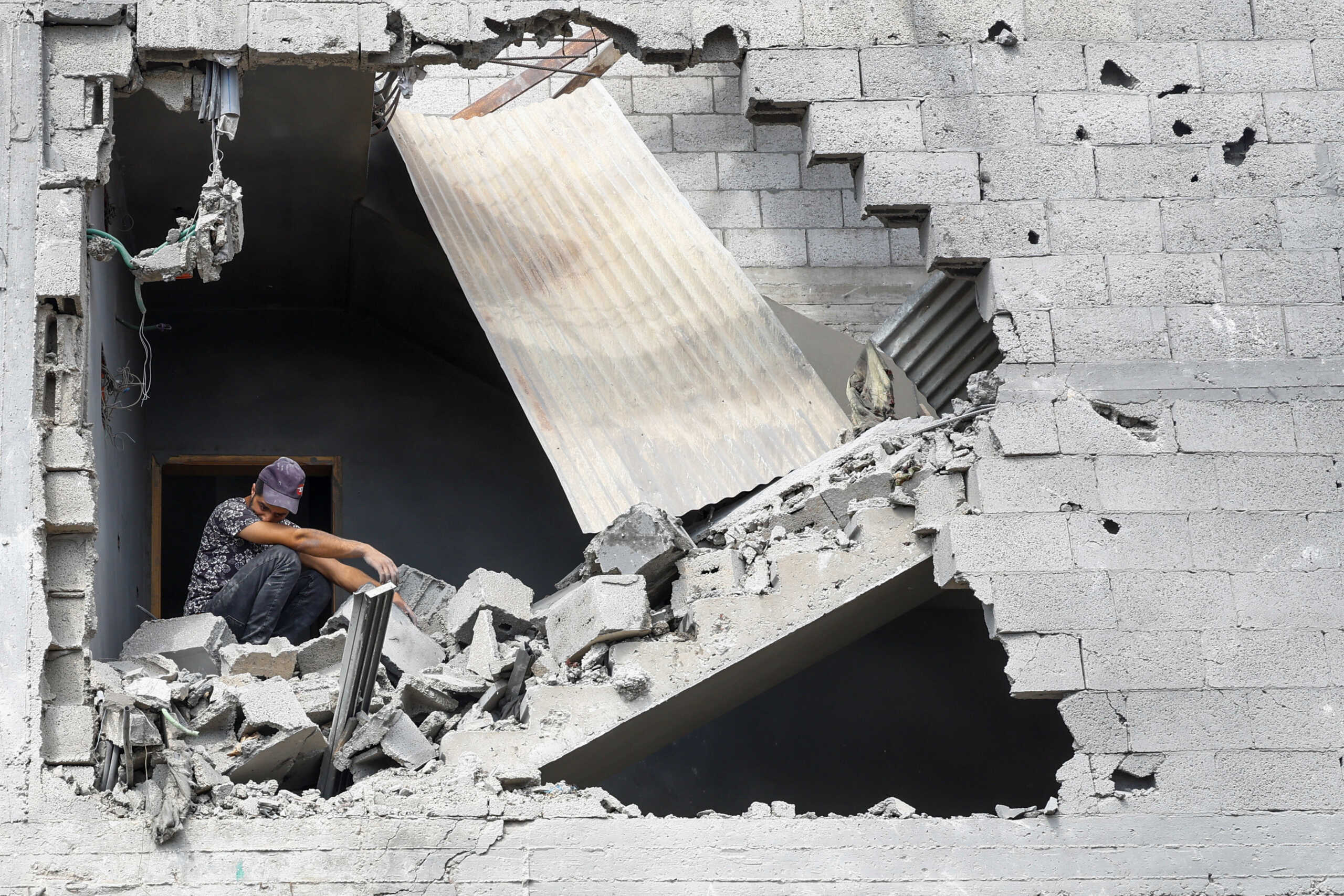 A man sits in the rubble as Palestinians search for casualties at a site of a house destroyed by Israeli strikes in Khan Younis in the southern Gaza Strip October 16, 2023. REUTERS
