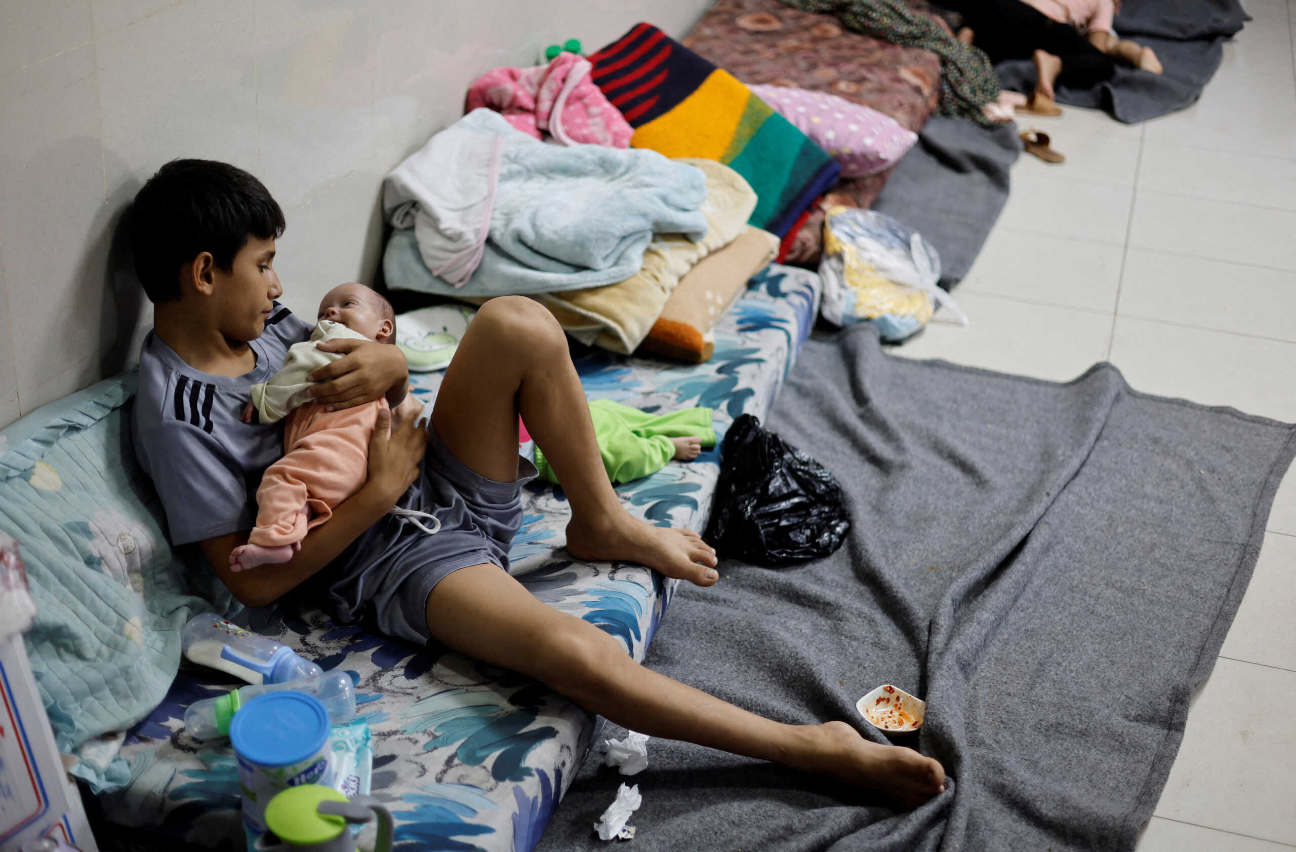 A displaced Palestinian boy, who fled with his family from their house amid Israeli strikes, looks after his twin siblings as they take shelter at Nasser hospital in Khan Younis in the southern Gaza Strip October 29, 2023. REUTERS