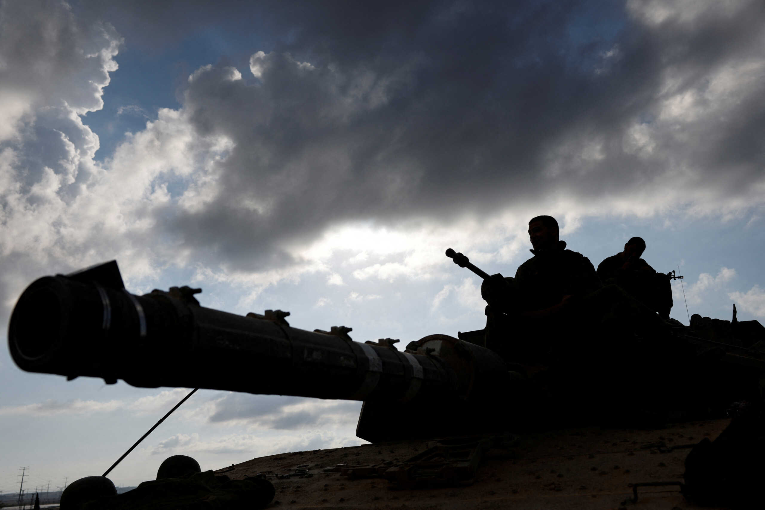 Israeli soldiers are silhouetted as they sit astride an Israeli tank near Israel's border with the Gaza Strip, in southern Israel October 15, 2023. REUTERS