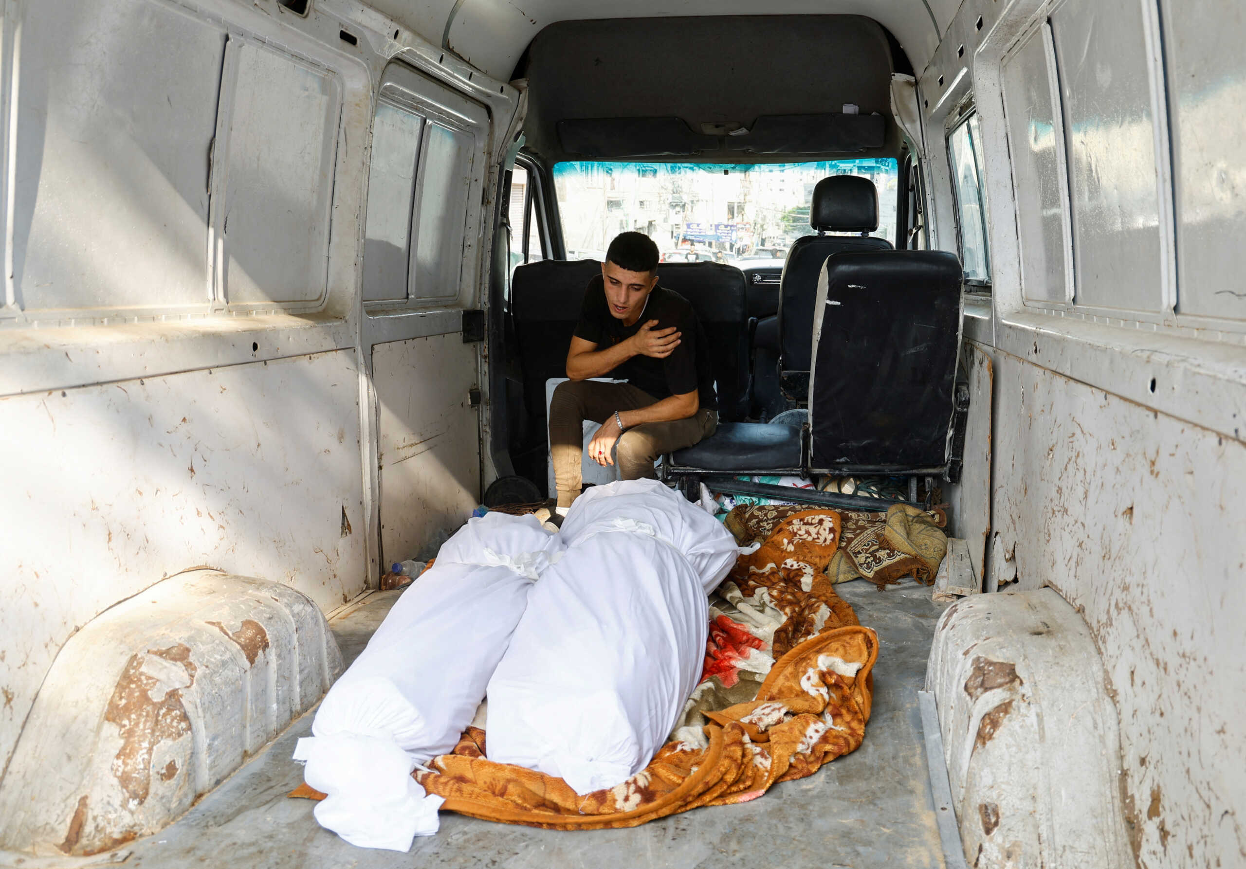 A relative reacts next to the bodies of Palestinians killed in Israeli strikes, at a hospital in Gaza City, October 11, 2023. REUTERS