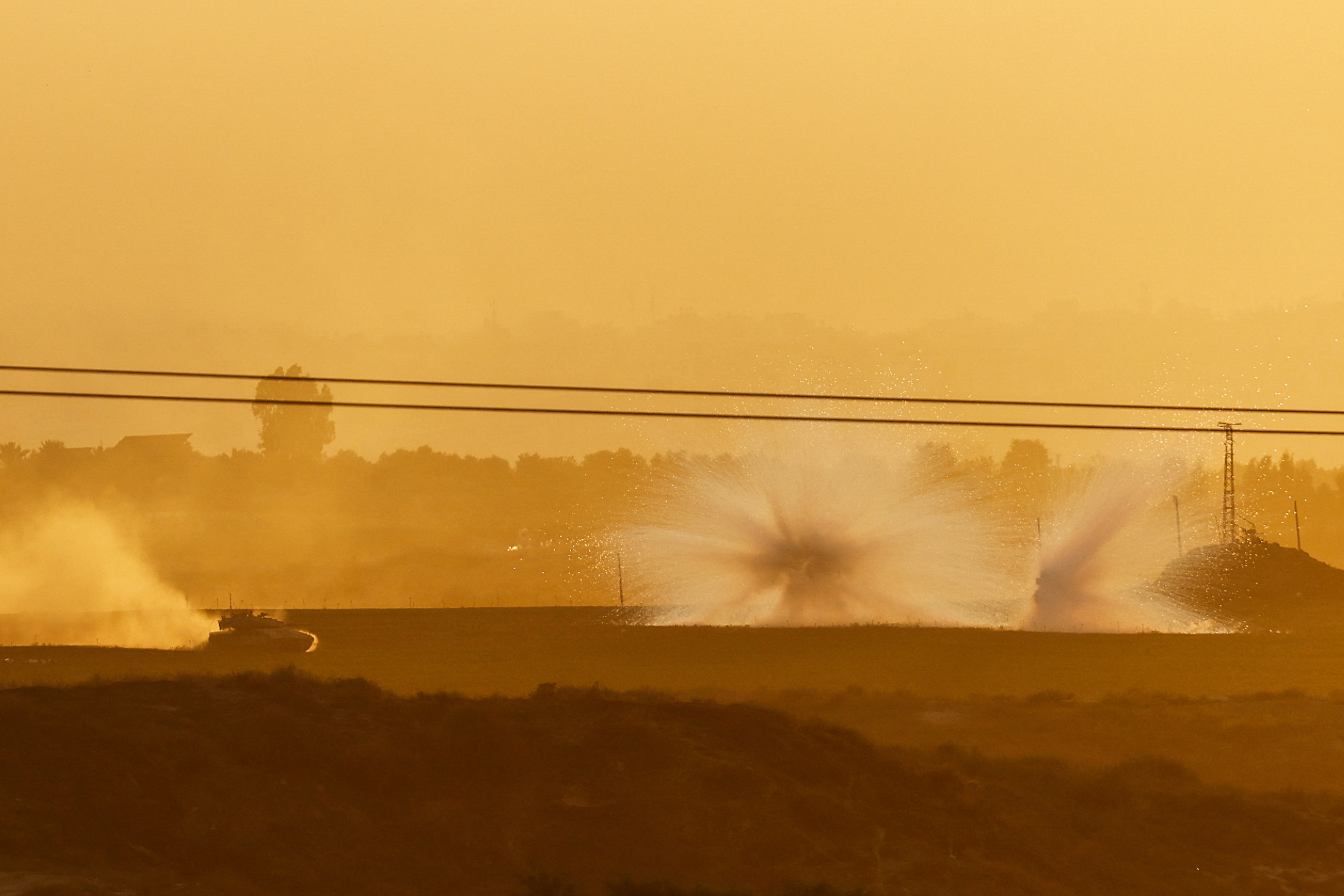 An Israeli tank manoeuvres and explosions are seen inside the Gaza Strip, as pictured from Israel, October 29, 2023. REUTERS
