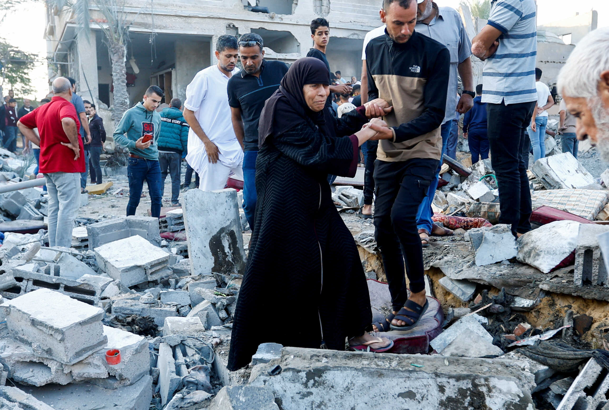 People walk on rubble in the aftermath of a strike amid the conflict with Israel in Khan Younis, in the southern Gaza Strip, October 12, 2023. REUTERS
