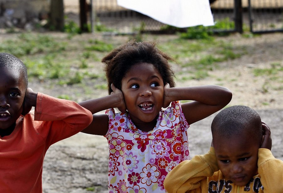 epa02194930 South African children cover their ears due to noise made by an artist (unseen) cutting a 'Makarepa' fan hat in his home backyard at Walmer neighborhood in Port Elizabeth, South Africa, 10 June 2010. The Makarapa is a hand-cut and hand painted hard hat. The origin of the term 'Makarapa' goes back to the late 70's and early 80's. It's derived from Makarapa, meaning migrant worker and is associated with the 'helmets' because they were used by migrant workers in the mines around Johannesburg. It belongs to the typical South African football fan's supporters gear and is increasingly popular with fans of other sports. Sport fans spend hours to sculpture and paint their Makarapa in the colours and emblem of their clubs or country. With the FIFA World Cup 2010, the international profile and availability of the Makarapa has increased greatly. The price of a Makarapa made from an artist varies between 180 and 500 ZAR (19 and 54 euro), depending on the quality and intricacy of the artwork. The FIFA 2010 Soccer World Cup is due to kick off on June 11.  EPA