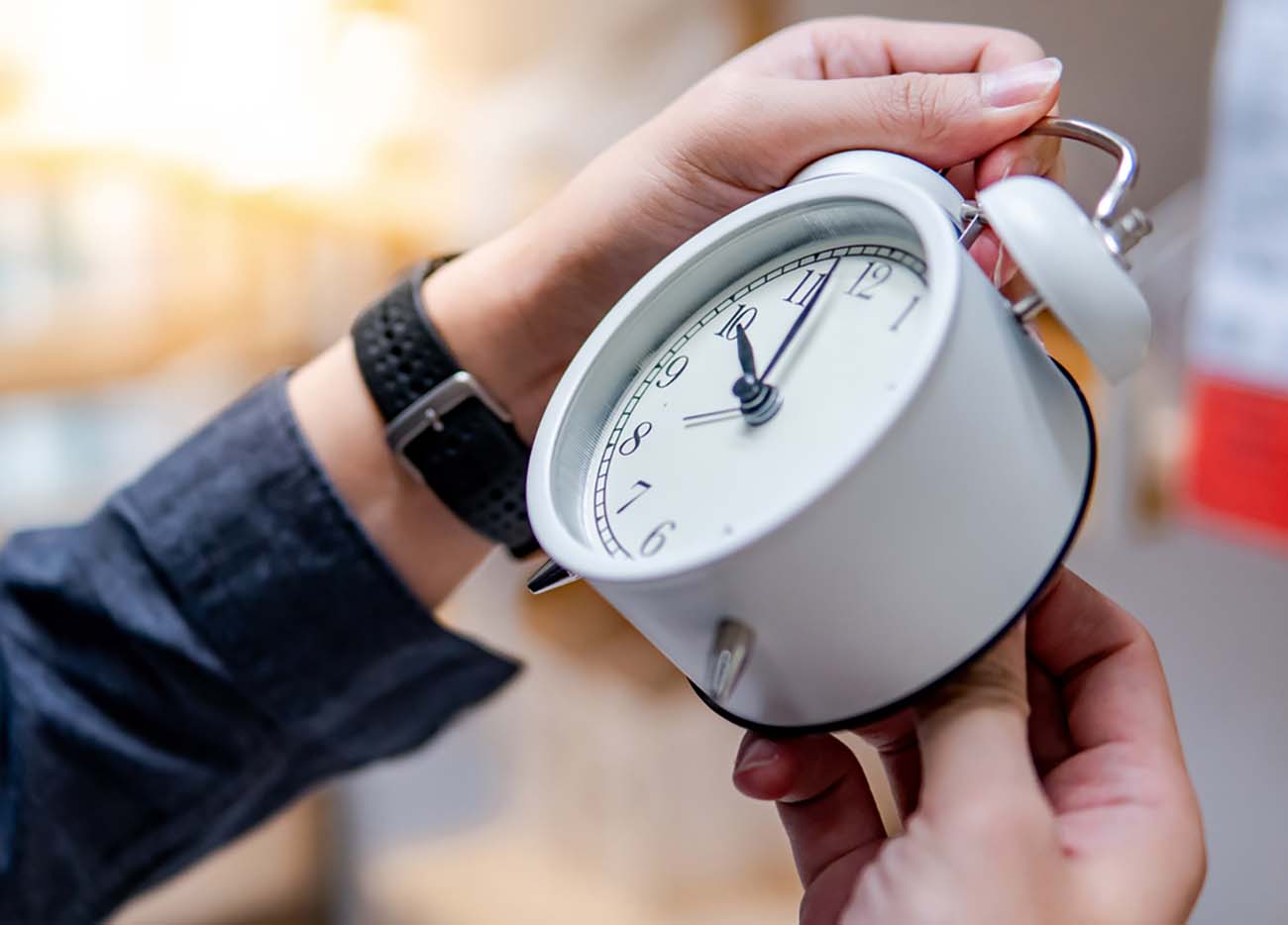 Male hand adjusting or changing the time on white clock. Time management concept.