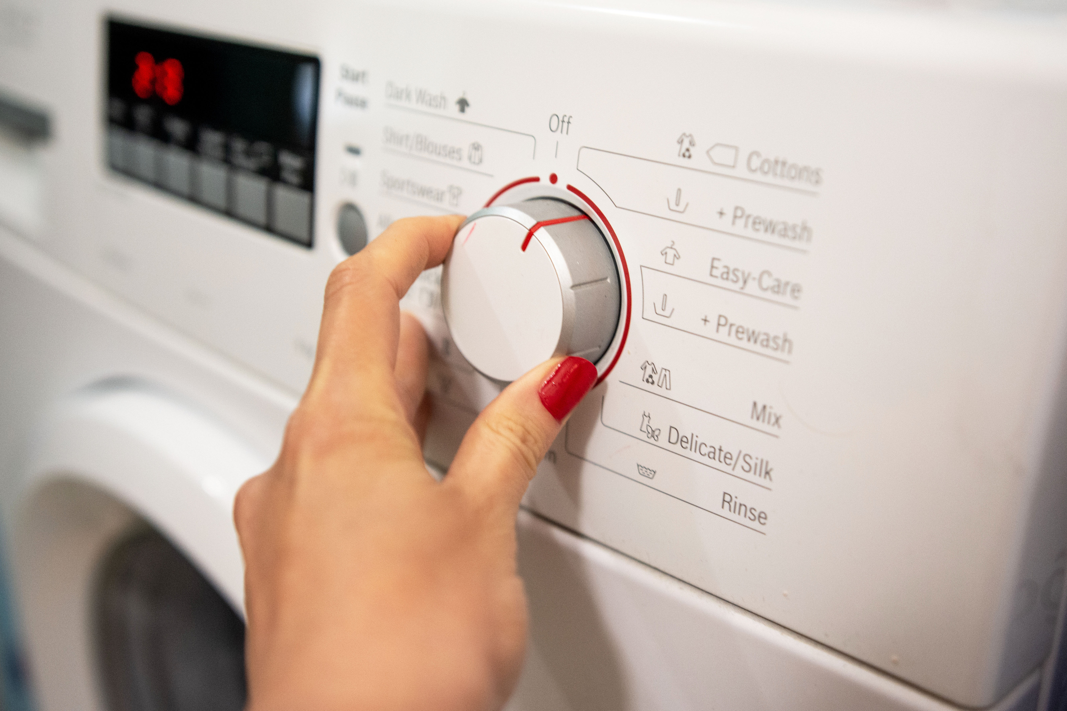 Close up of woman choosing cycle program on washing machine
