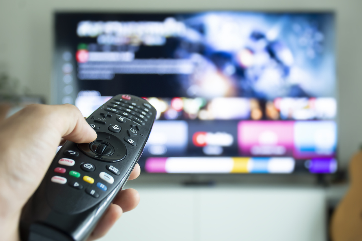 Hand holding a remote to browse TV shows or series.