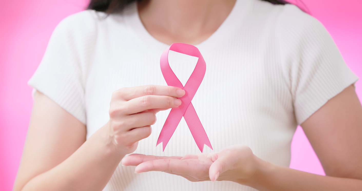 Healthcare concept - close up asian woman is holding the pink ribbon breast cancer symbol to encourage patient fighting illness