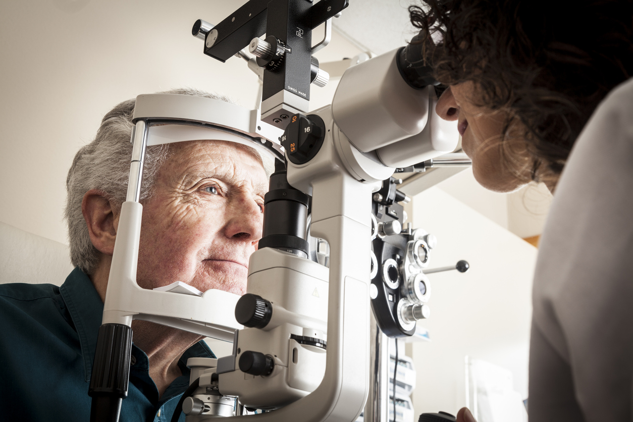 Optometrist giving eye exam to senior patient