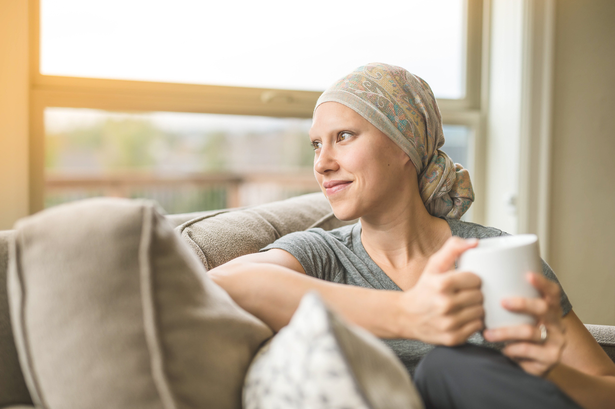 Ethnic young adult female cancer patient sipping tea while at home