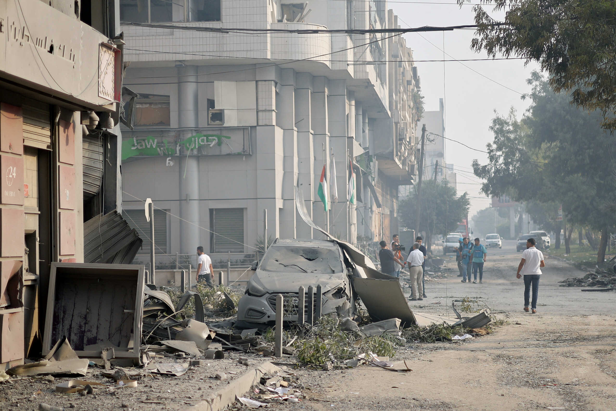 Palestinians walk on a street near the Watan Tower, which was destroyed in Israeli strikes, in Gaza City October 8, 2023. REUTERS