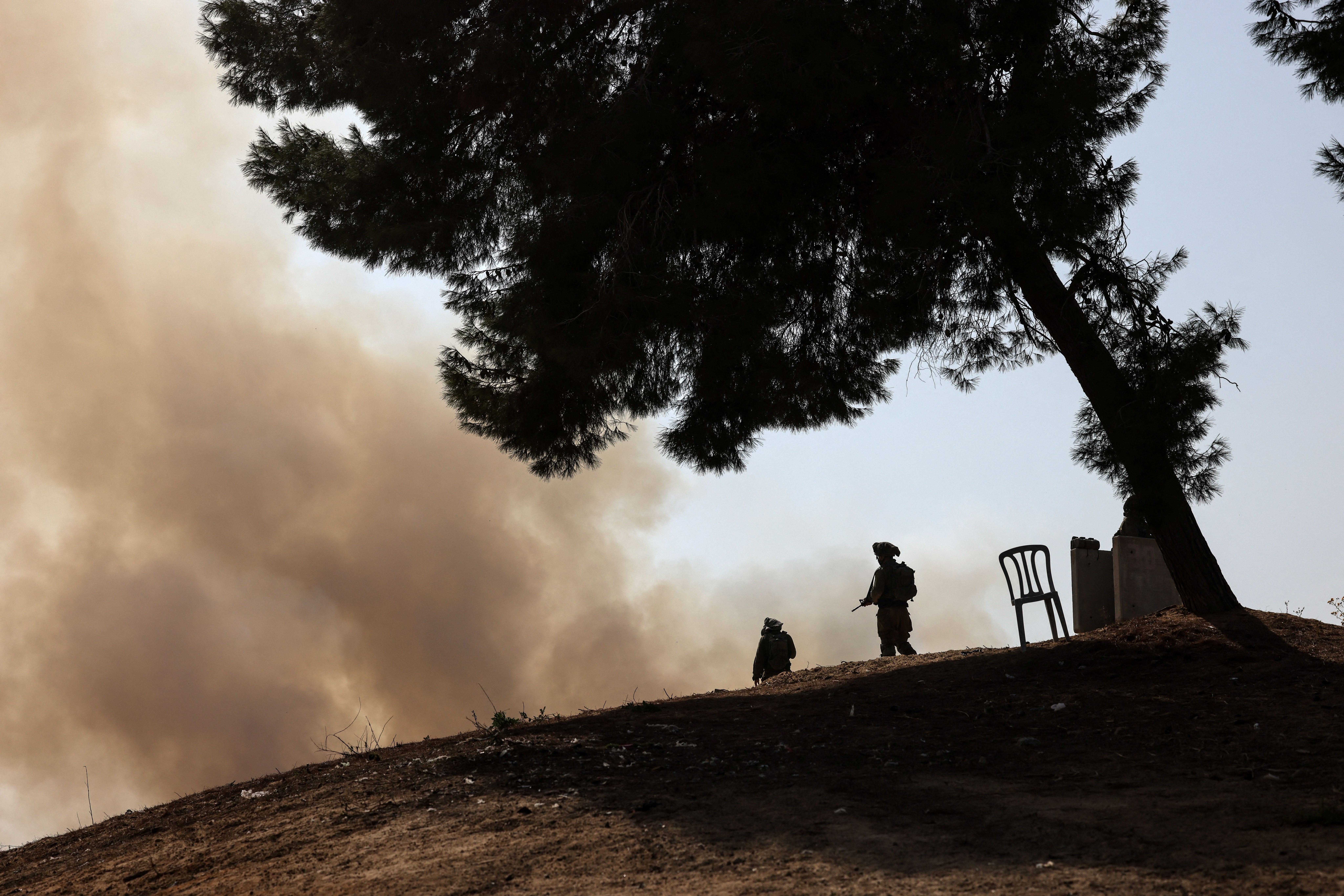 Israeli soldiers stand guard and look at a fire that was caused when a rocket that was launched from Gaza landed in southern Israel, October 24, 2023. REUTERS