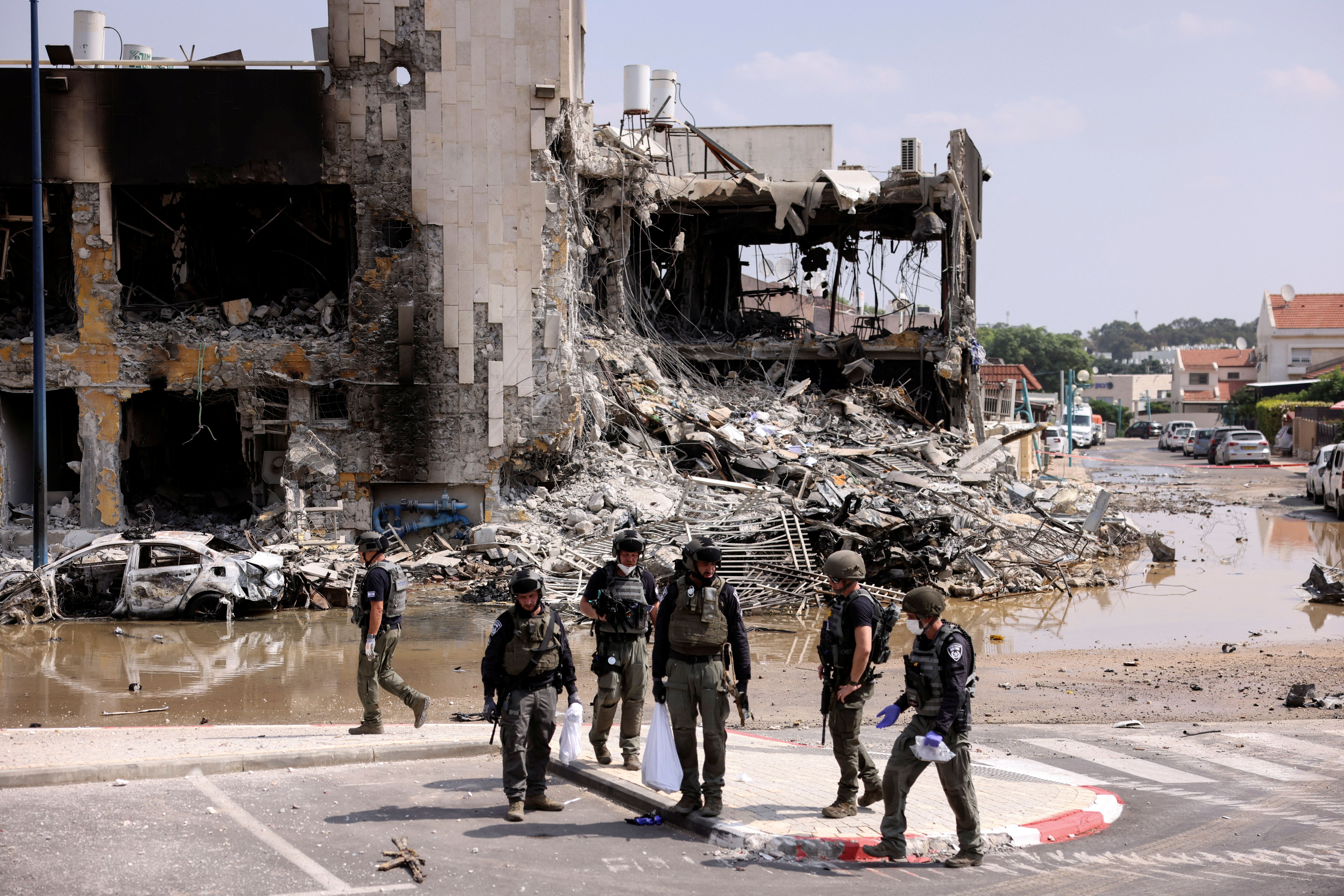 Israeli security gather near a rifle at the site of a battle following a mass infiltration by Hamas gunmen from the Gaza Strip, in Sderot, southern Israel October 8, 2023. REUTERS