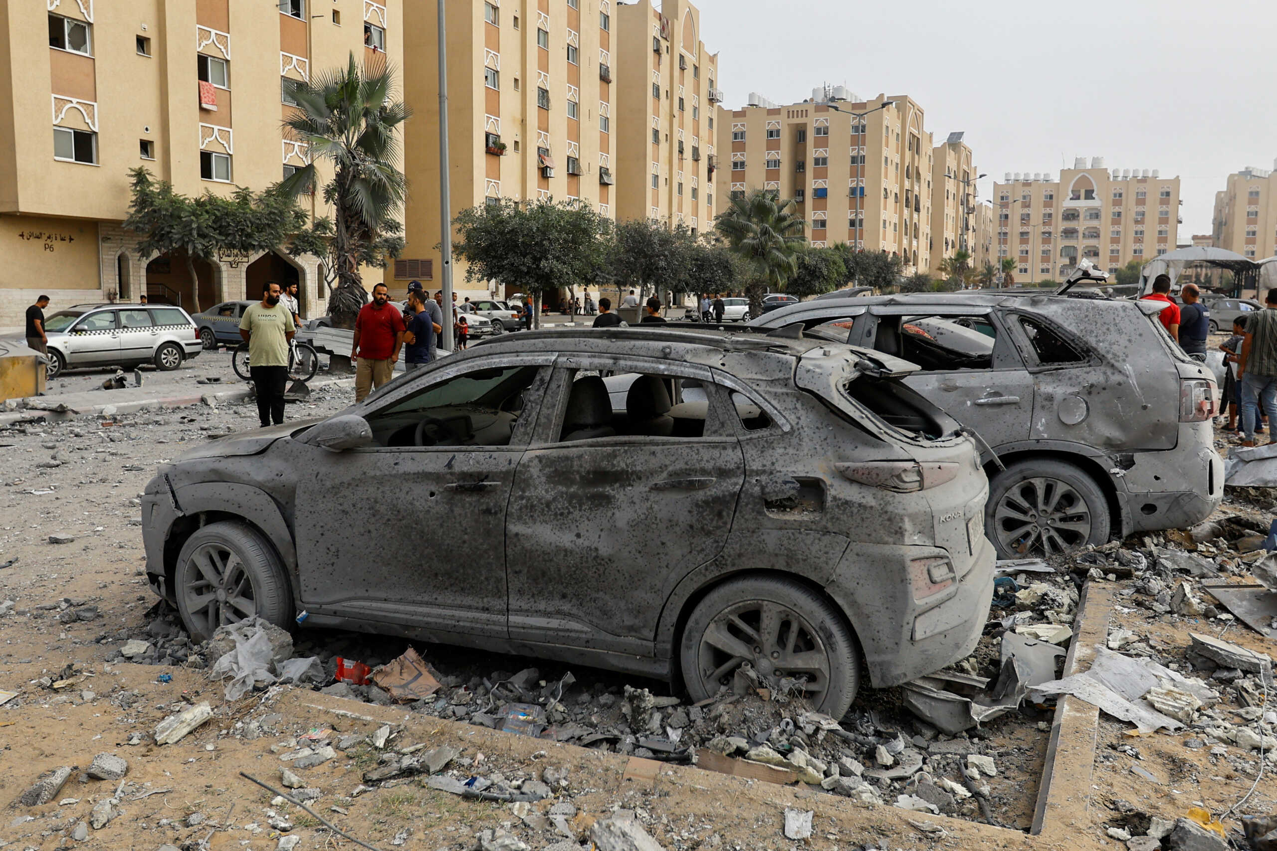 Palestinians look at damaged vehicles near the site of Israeli strikes on a house in Khan Younis in the southern Gaza Strip, October 23, 2023. REUTERS