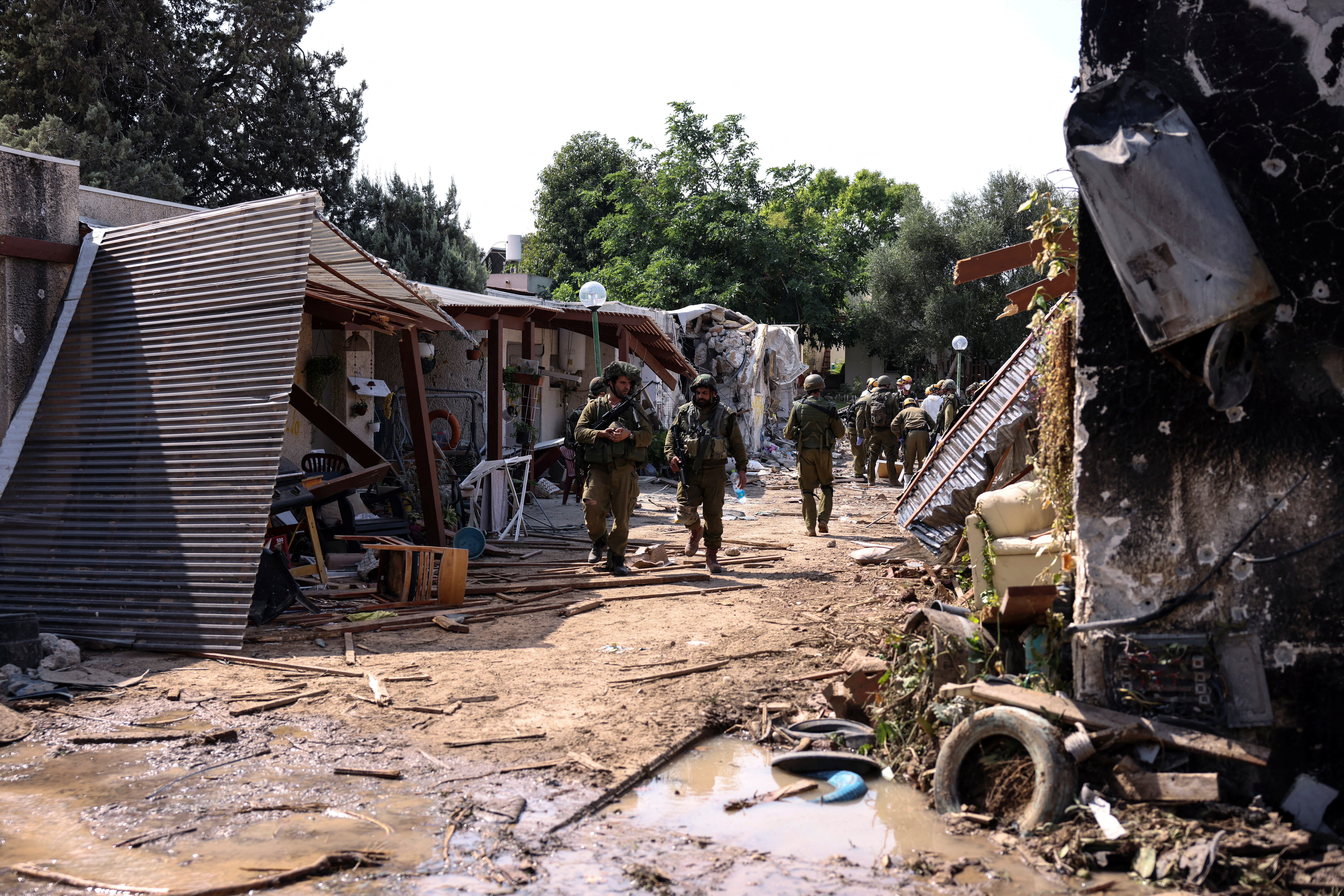 Israeli soldiers walk through the remains of a residential area of Kibbutz Kfar Aza, in southern Israel, October 10, 2023. REUTERS