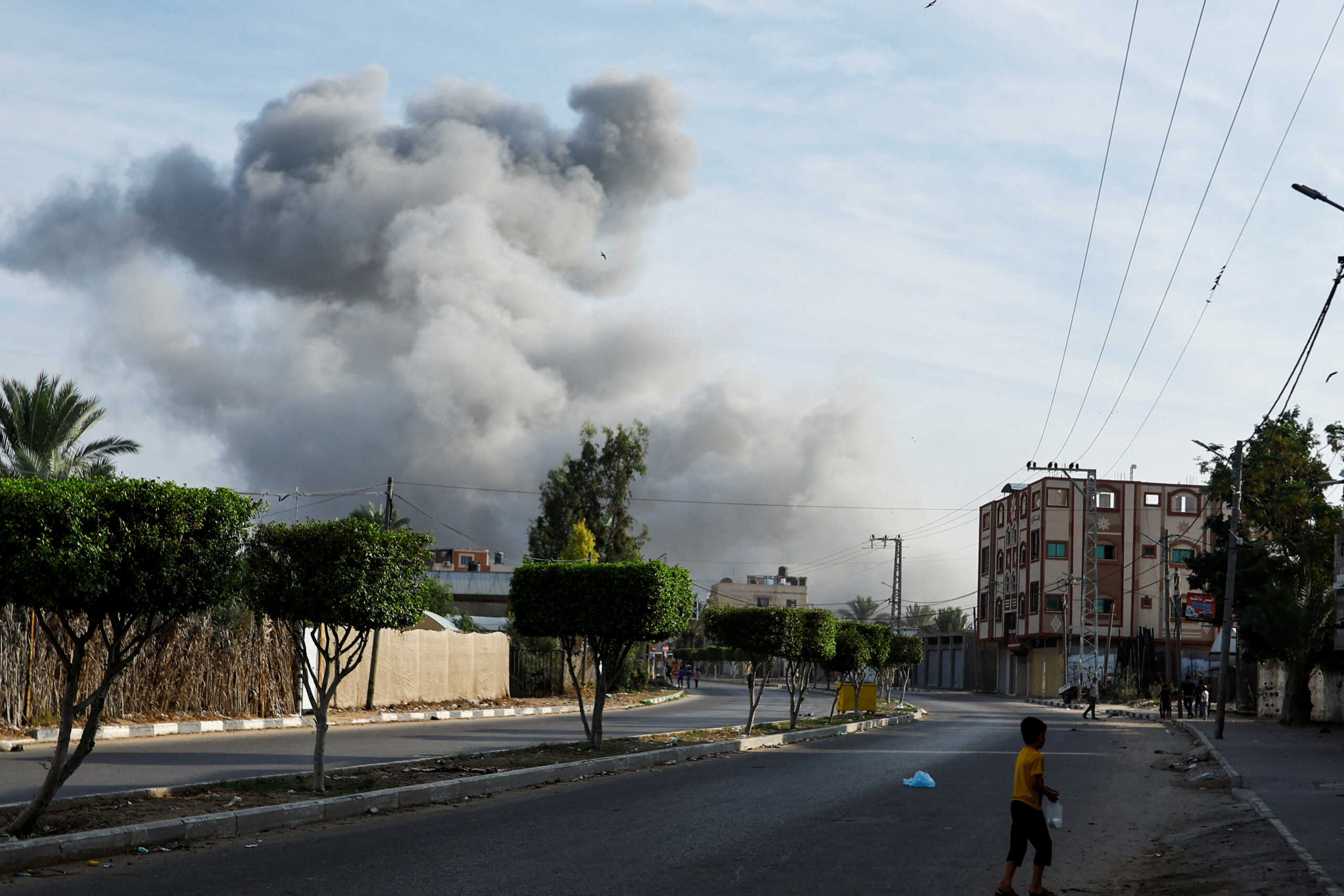 Palestinians walk in an empty street as smoke rises nearby in the aftermath of Israeli strikes, in Khan Younis in the southern Gaza Strip October 11, 2023. REUTERS