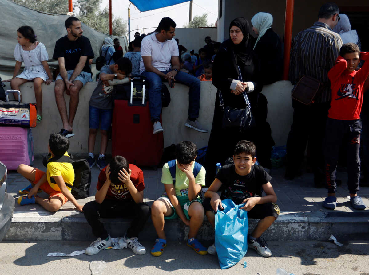 Palestinians with dual citizenship wait outside Rafah border crossing with Egypt in the hope of getting permission to leave Gaza, amid the ongoing Israeli-Palestinian conflict, in Rafah in the southern Gaza Strip October 14, 2023. REUTERS