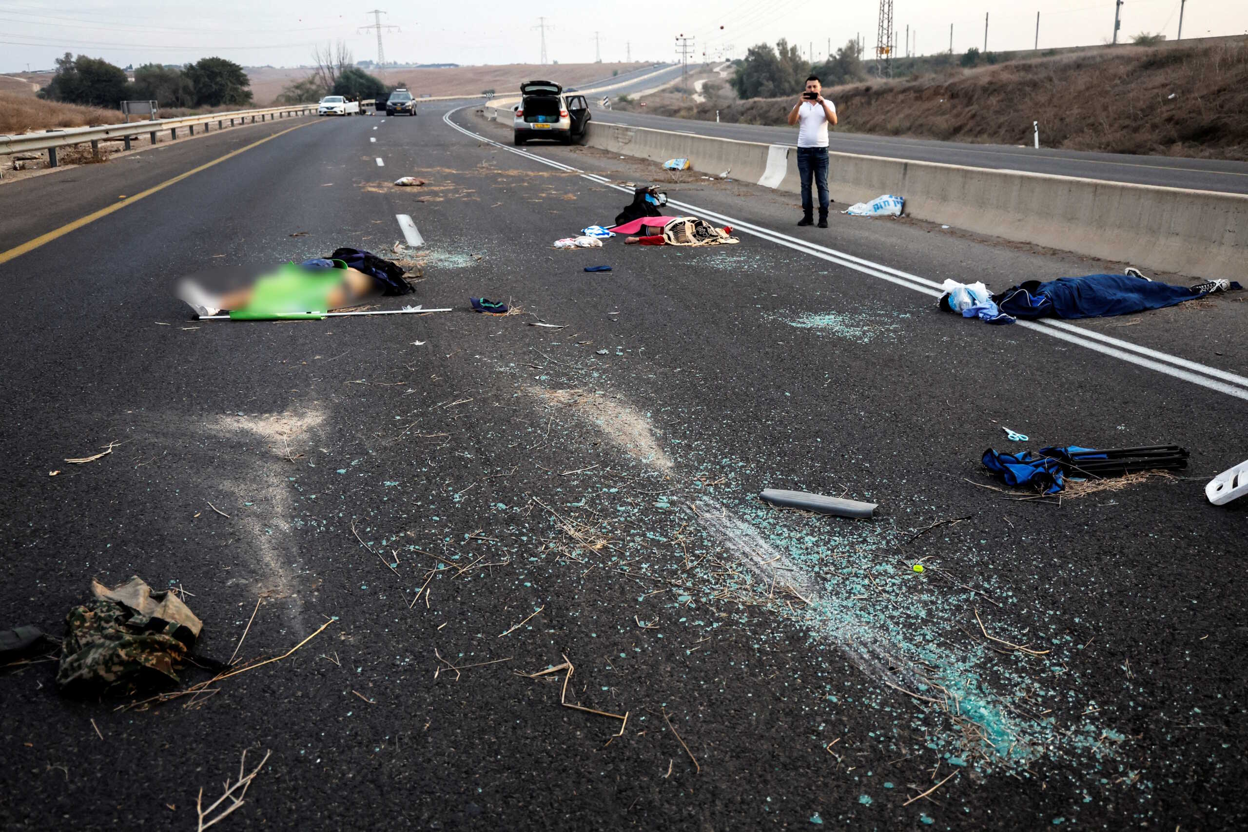 SENSITIVE MATERIAL. THIS IMAGE MAY OFFEND OR DISTURB A man takes a photo of dead people strewn across a road following a mass-infiltration by Hamas gunmen from the Gaza Strip, in the Sderot area, southern Israel October 7, 2023. REUTERS